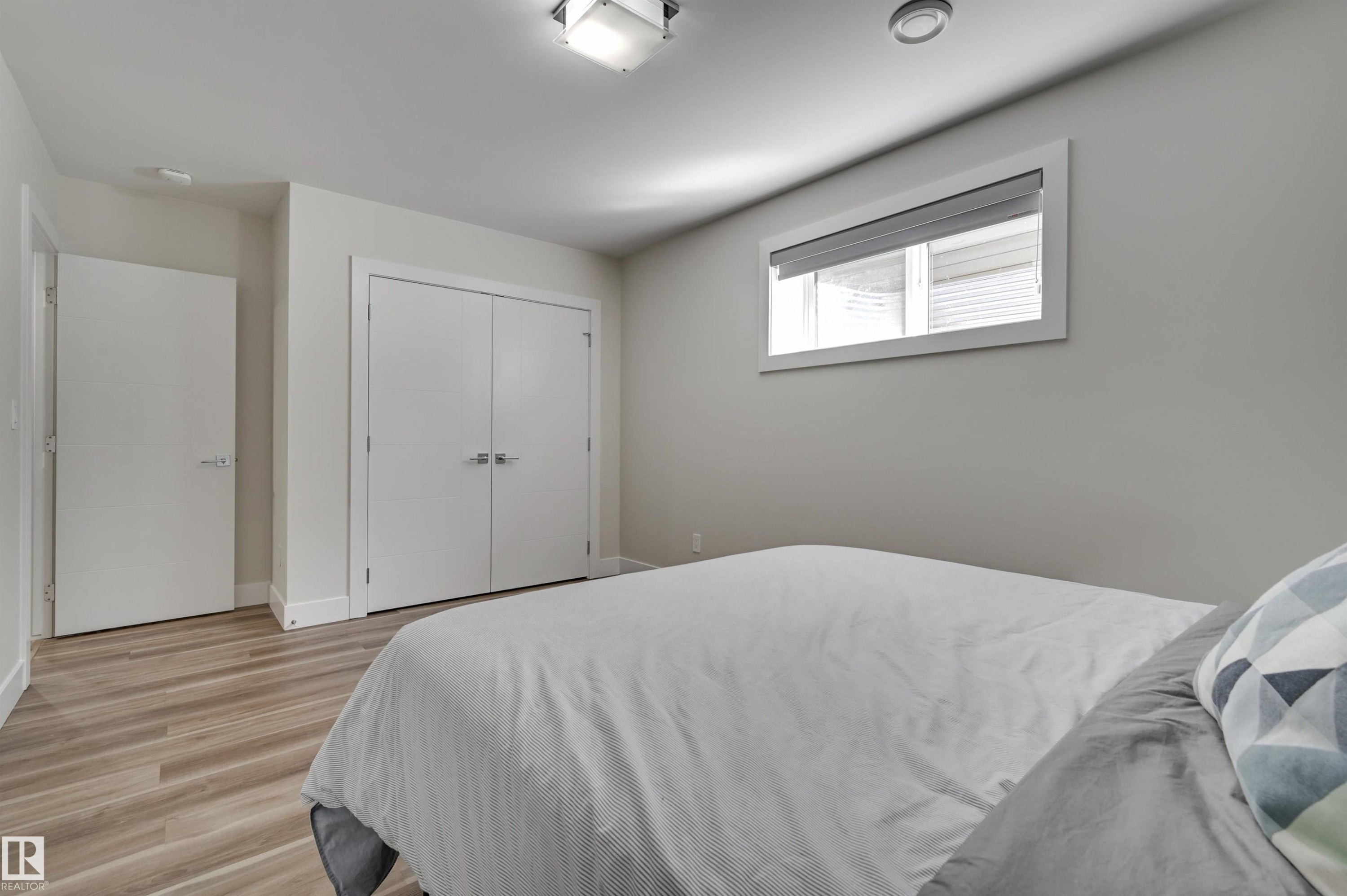 Spacious room featuring light wood-finish flooring, a double-door closet, a single window with blinds, and recessed ceiling lighting - 9741 90 Avenue, Edmonton, AB - Indoor Photo Showing Bedroom