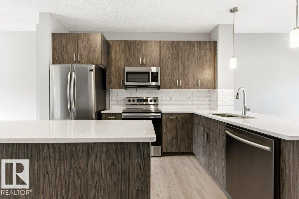 Kitchen featuring wood-finish cabinetry, stainless steel appliances, white subway tile backsplash, and light-toned wood-finish flooring - 17451 77 Street, Edmonton, AB - Indoor Photo Showing Kitchen With Upgraded Kitchen