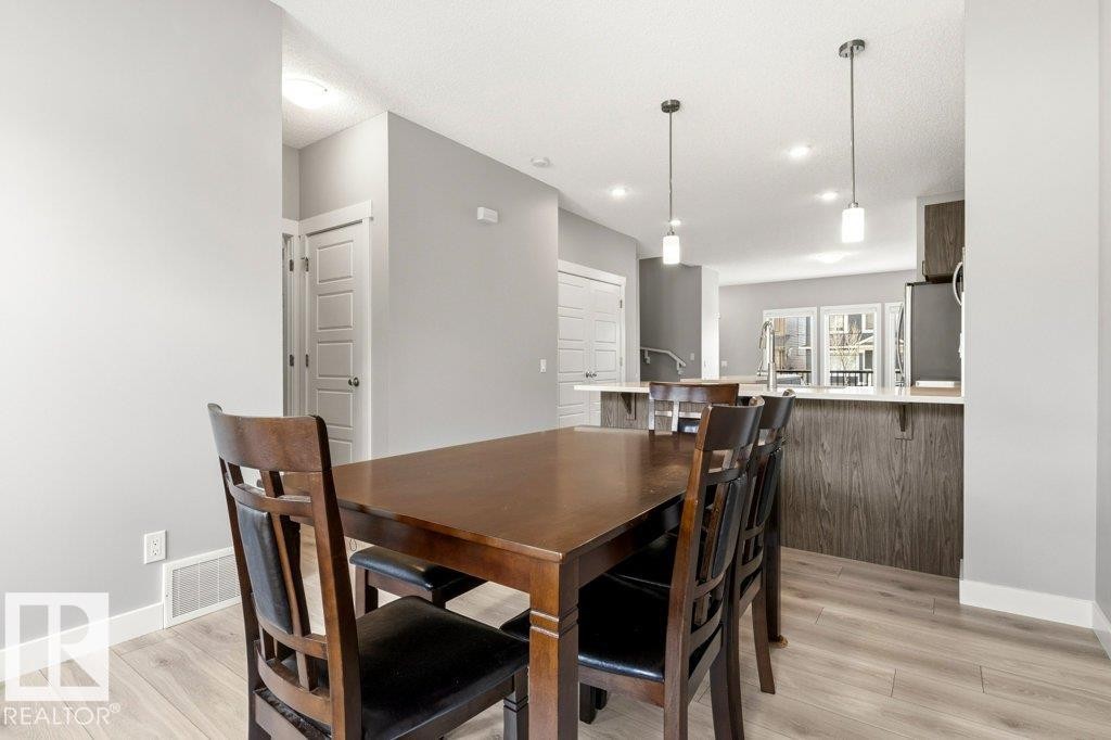 Open-concept dining area featuring light-toned wood-finish flooring, recessed lighting, and modern pendant fixtures - 17451 77 Street, Edmonton, AB - Indoor Photo Showing Dining Room