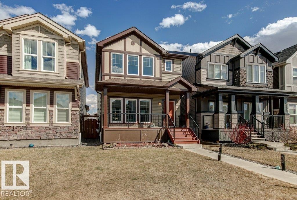 Contemporary two-story residence featuring a covered front porch with dark railing, a front door with sidelight, and a front-facing bay window - 17451 77 Street, Edmonton, AB - Outdoor With Facade