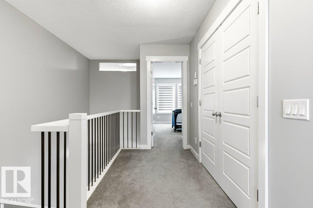 Upper-level hallway featuring a contemporary white railing with black spindles, light gray walls, and plush carpeting - 17451 77 Street, Edmonton, AB - Indoor Photo Showing Other Room