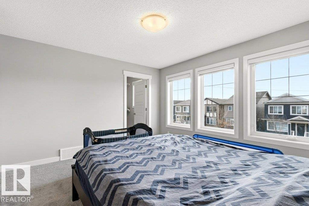 Room featuring three large windows, light gray wall paint, white trim, carpet flooring, and a flush mount ceiling light fixture - 17451 77 Street, Edmonton, AB - Indoor Photo Showing Bedroom