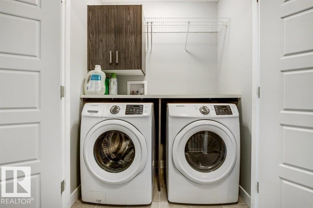 Dedicated laundry area featuring a wood-finish upper cabinet, wire shelving, and a solid surface countertop - 17451 77 Street, Edmonton, AB - Indoor Photo Showing Laundry Room