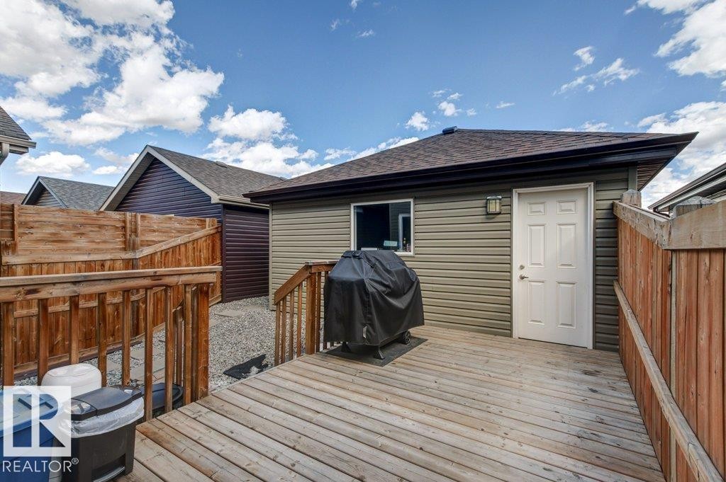 Spacious wood-finish deck with wooden railings, featuring a side door entry and an exterior light fixture - 17451 77 Street, Edmonton, AB - Outdoor With Deck Patio Veranda With Exterior
