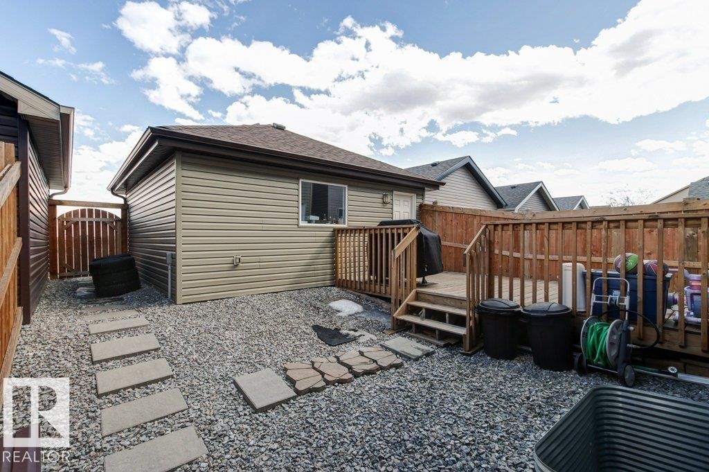 Expansive gravel yard featuring a raised wood deck with railing, a detached outbuilding with siding, a wood privacy fence, and stepping stone pathways - 17451 77 Street, Edmonton, AB - Outdoor With Exterior