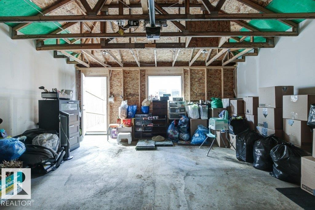 Unfinished garage interior featuring exposed ceiling joists, concrete flooring, and an exterior access door - 17451 77 Street, Edmonton, AB - Indoor