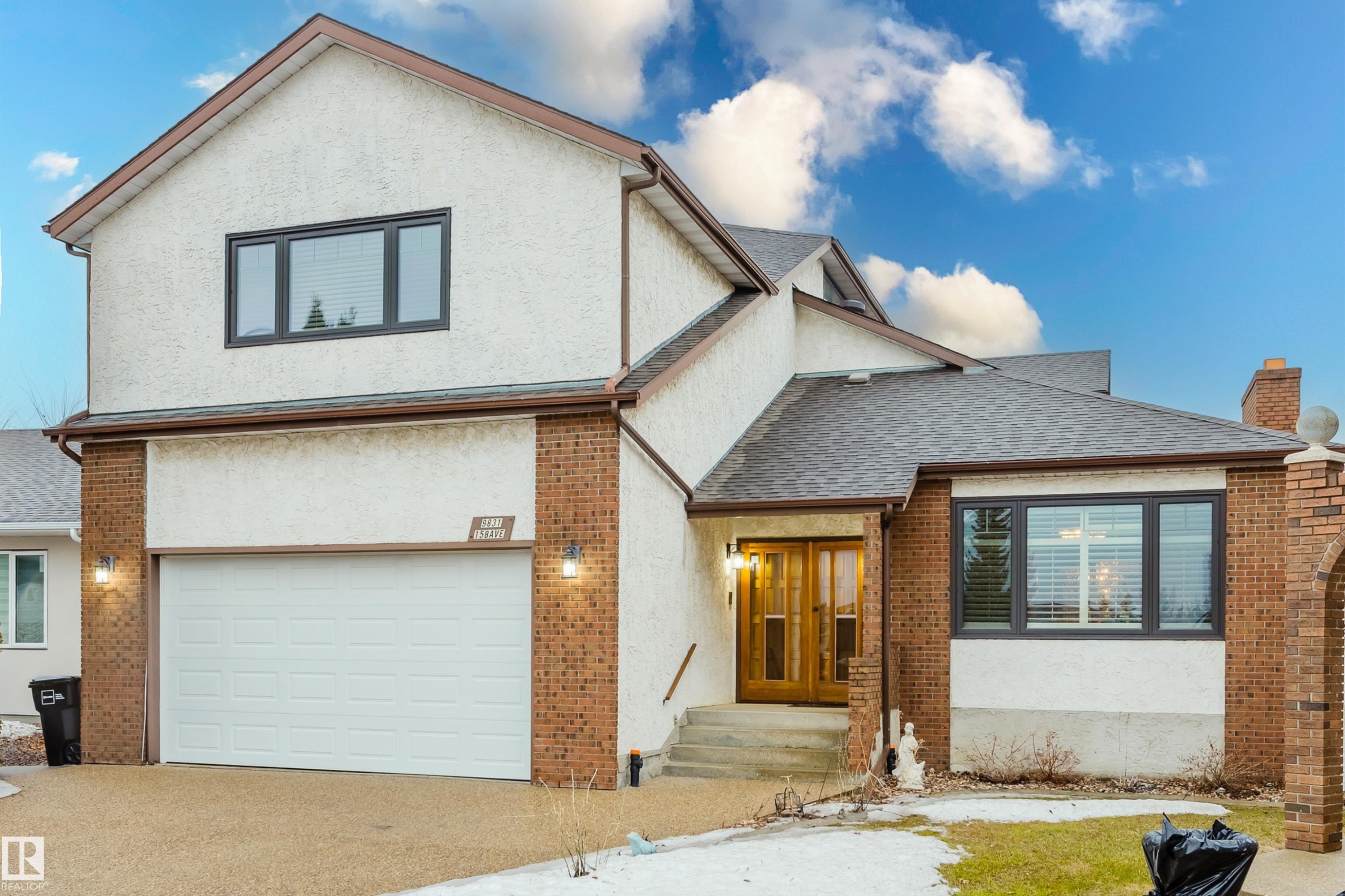 Exterior featuring stucco and brick finishes, an attached garage, a multi-pitched roofline, and a double-door entryway - 9831 158 Avenue, Edmonton, AB - Outdoor