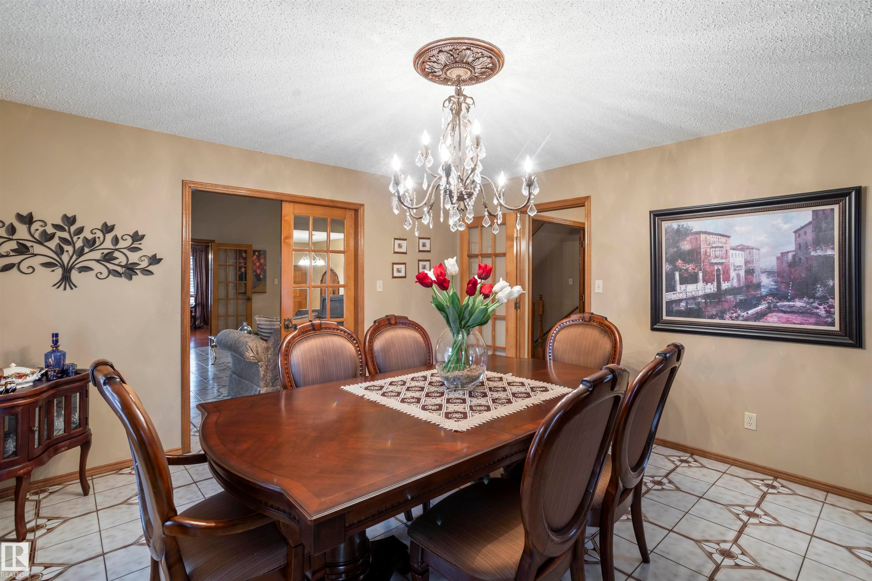 Dining area featuring a decorative chandelier with crystal accents, light beige wall paint, and patterned tile flooring - 9831 158 Avenue, Edmonton, AB - Indoor Photo Showing Dining Room