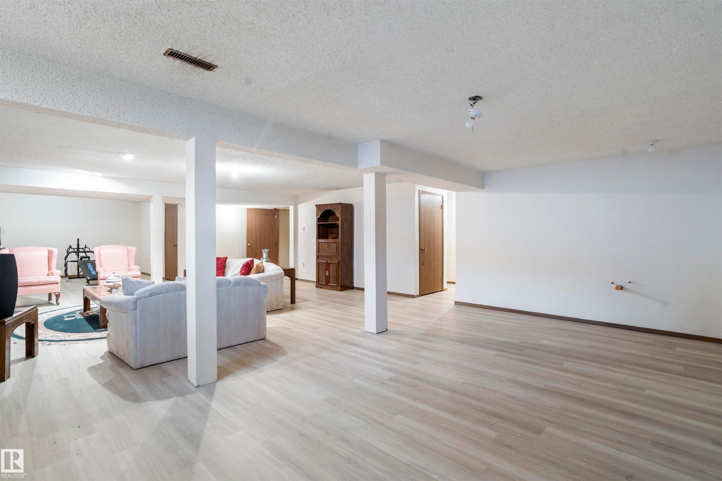Spacious finished basement featuring light wood-finish flooring, recessed lighting, and support columns - 9831 158 Avenue, Edmonton, AB - Indoor