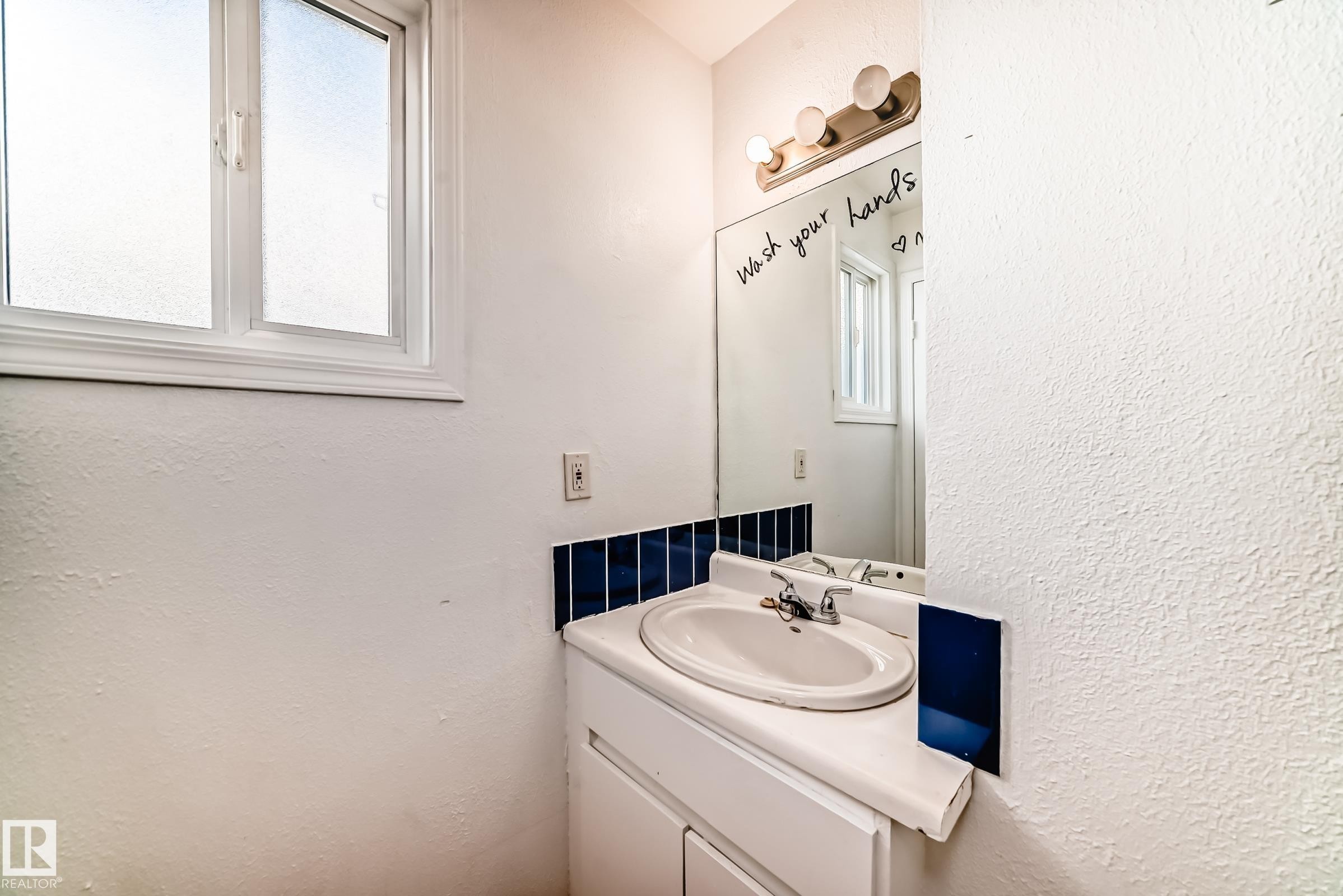 Bathroom vanity with an integrated sink, chrome faucet, and a large mirror - 8217 182 Street Nw, Edmonton, AB - Indoor Photo Showing Bathroom