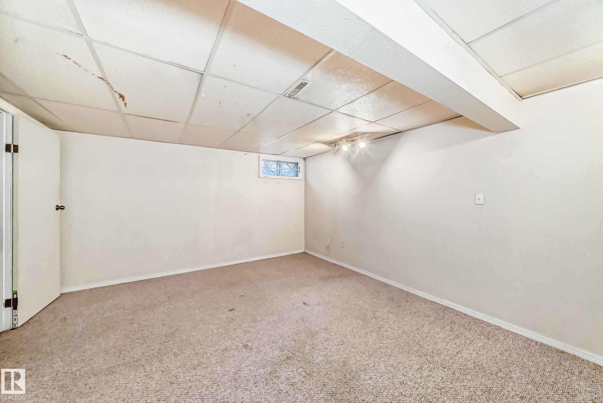 Spacious room featuring neutral carpeting, light-colored walls, and a drop ceiling with integrated lighting - 8217 182 Street Nw, Edmonton, AB - Indoor Photo Showing Other Room