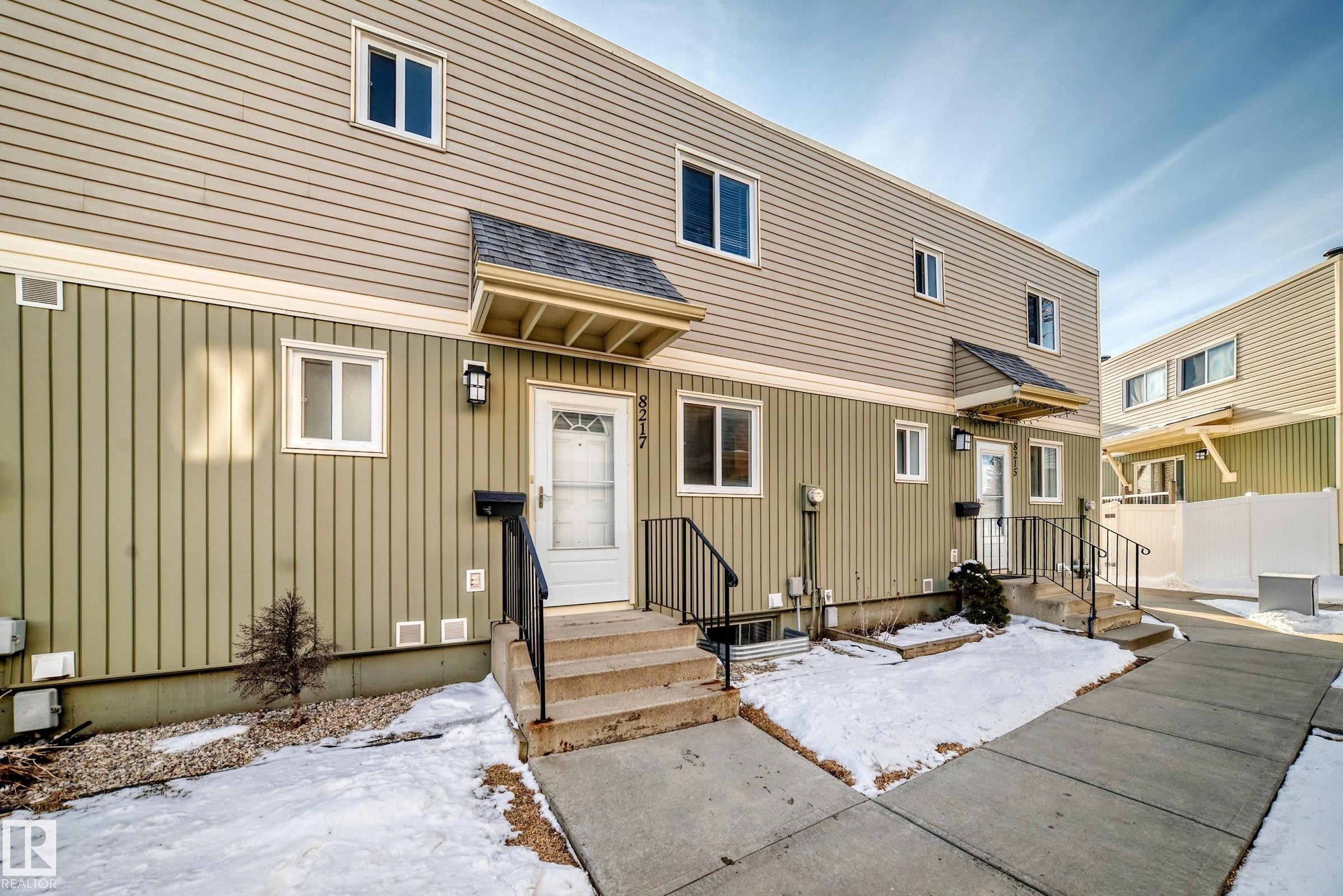 The property features vertical siding on the lower level and horizontal siding on the upper level, with a white entry door and a covered porch - 8217 182 Street Nw, Edmonton, AB - Outdoor