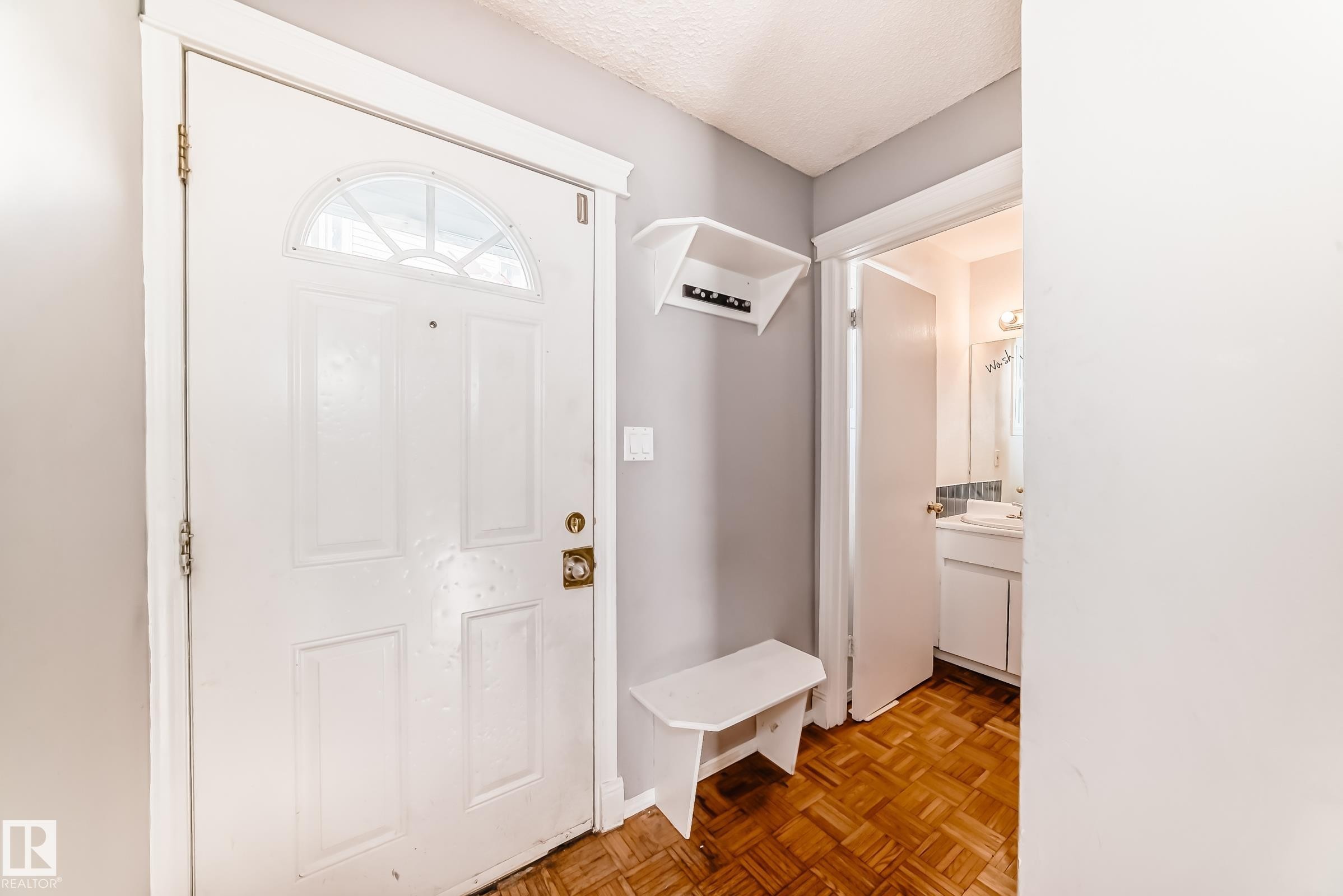 Entryway featuring a white door with an arched window, wood parquet flooring, and a built-in shelf with hooks - 8217 182 Street Nw, Edmonton, AB - Indoor Photo Showing Other Room