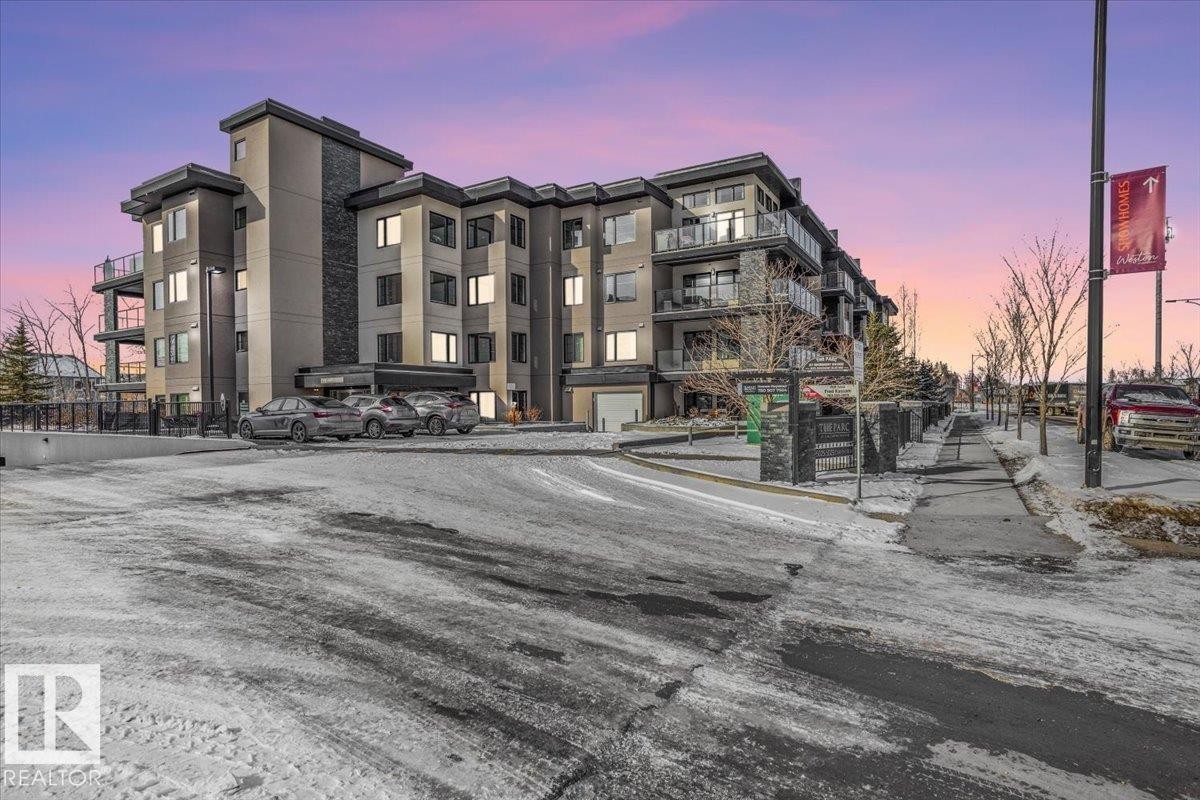 The property features a multi-story building with a modern architectural style, incorporating stone accents and balconies - 211 5029 Edgemont Boulevard, Edmonton, AB - Outdoor With Facade