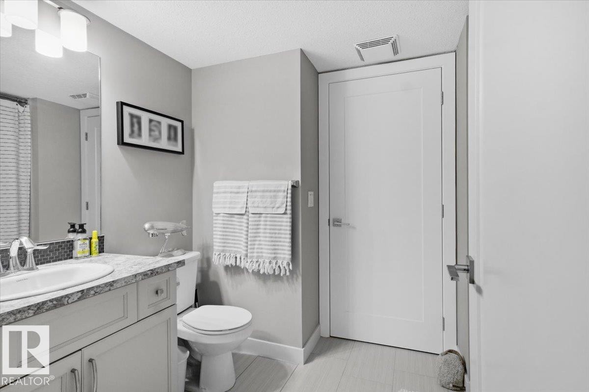 Bathroom featuring a vanity with an undermount sink, granite countertop, and mosaic tile backsplash - 211 5029 Edgemont Boulevard, Edmonton, AB - Indoor Photo Showing Bathroom