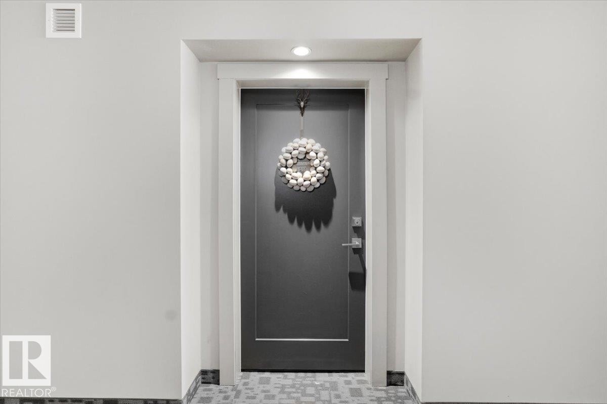 The property features a modern dark gray entrance door with white trim, complemented by a recessed light overhead - 211 5029 Edgemont Boulevard, Edmonton, AB - Photo Showing Other Room
