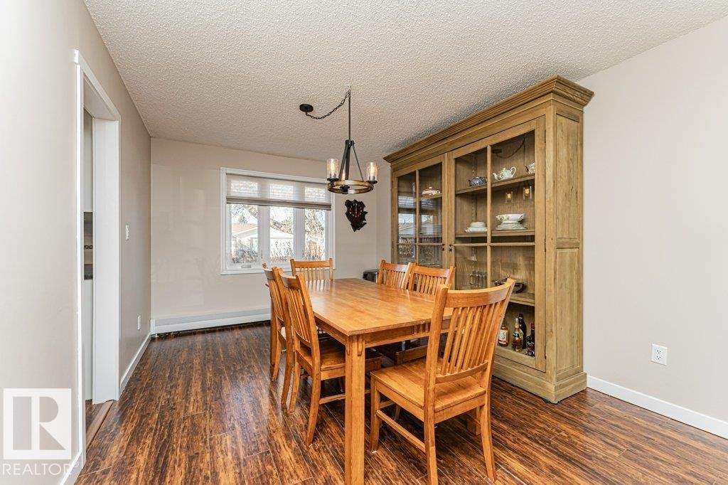 Dining area featuring wood-finish flooring, a contemporary chandelier, a window with blinds, and light-colored wall paint - 1727 65 Street, Edmonton, AB - Indoor Photo Showing Dining Room