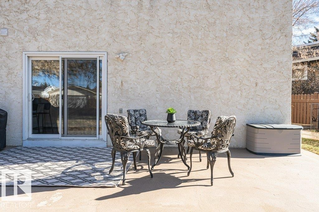 Private concrete patio featuring a textured stucco exterior and a large glass sliding door - 1727 65 Street, Edmonton, AB - Outdoor