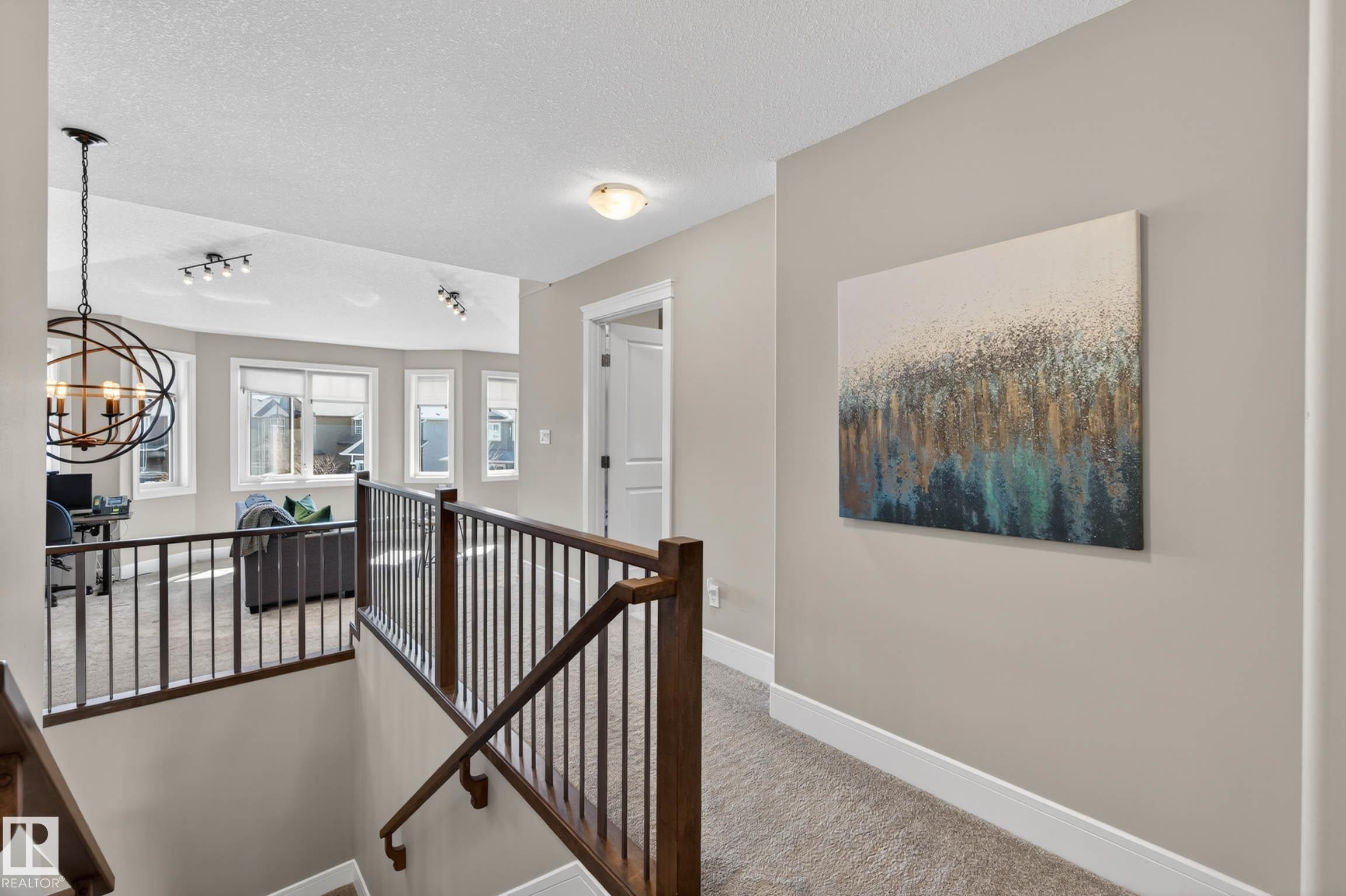 Upper-level landing featuring a wood and metal railing, light gray carpeting, and a neutral wall color - 2086 Redtail Common, Edmonton, AB - Indoor Photo Showing Other Room