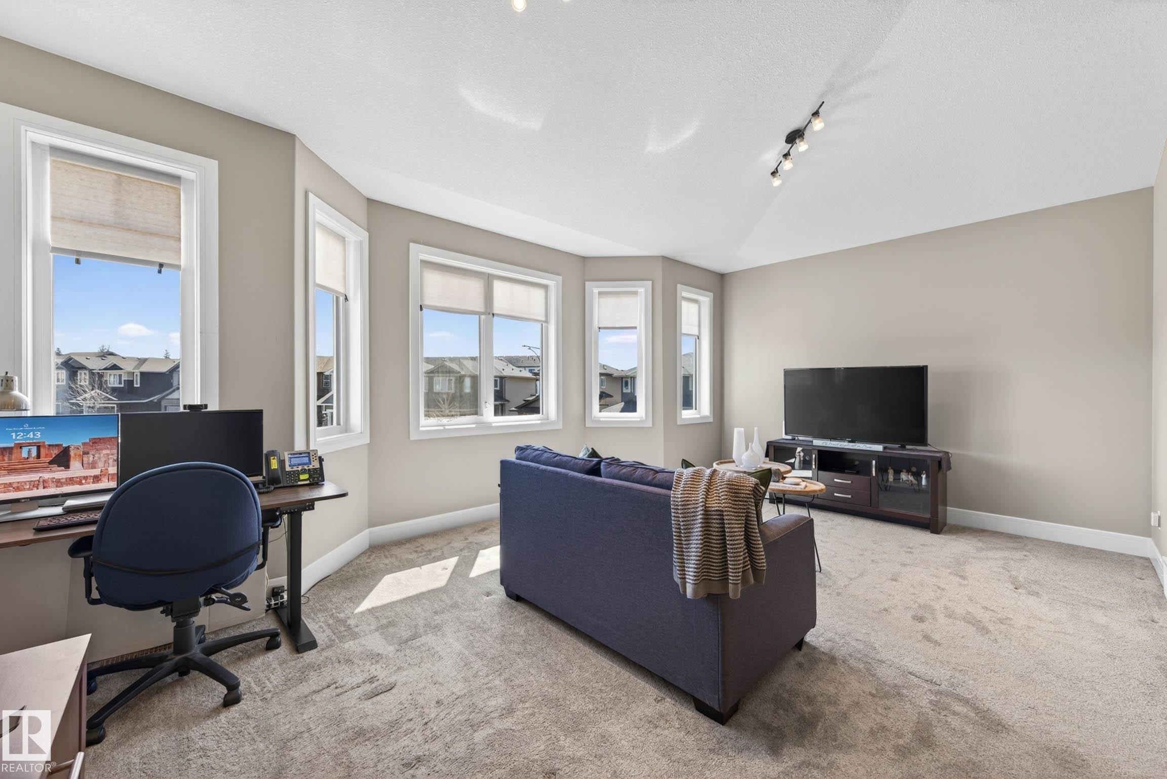 Carpeted room with multiple windows, track lighting, and neutral wall tones - 2086 Redtail Common, Edmonton, AB - Indoor