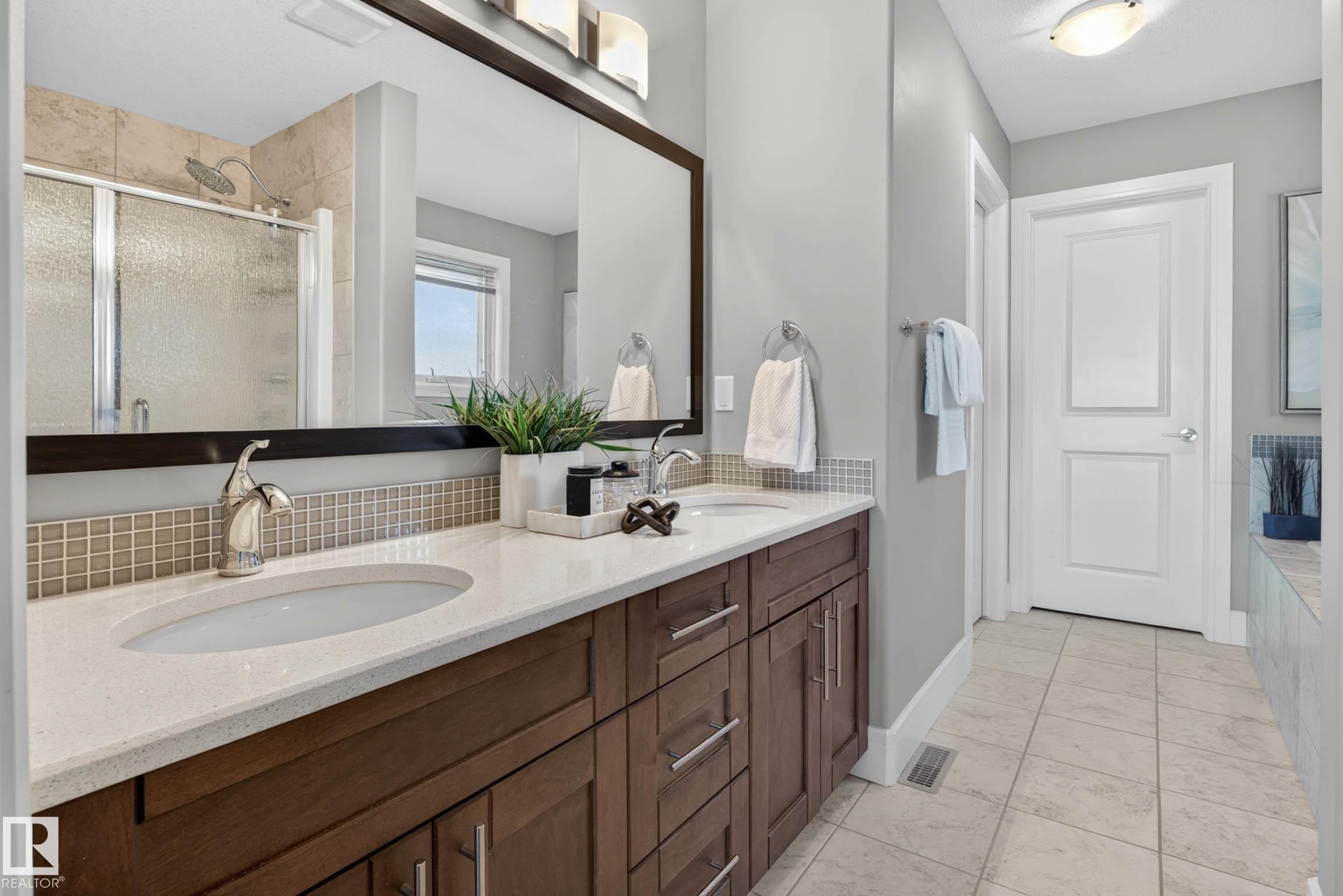 Bathroom featuring a double vanity with stone countertops, wood-finish cabinetry, and contemporary fixtures - 2086 Redtail Common, Edmonton, AB - Indoor Photo Showing Bathroom