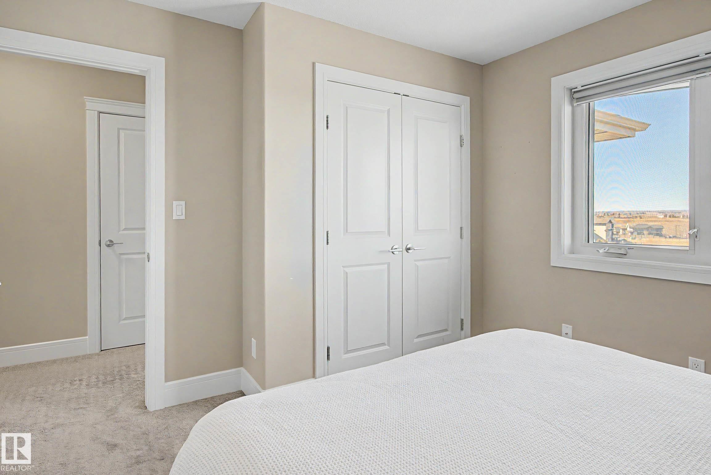 Bedroom featuring neutral-toned walls, white trim, and a double-door closet with polished chrome hardware - 2086 Redtail Common, Edmonton, AB - Indoor Photo Showing Bedroom