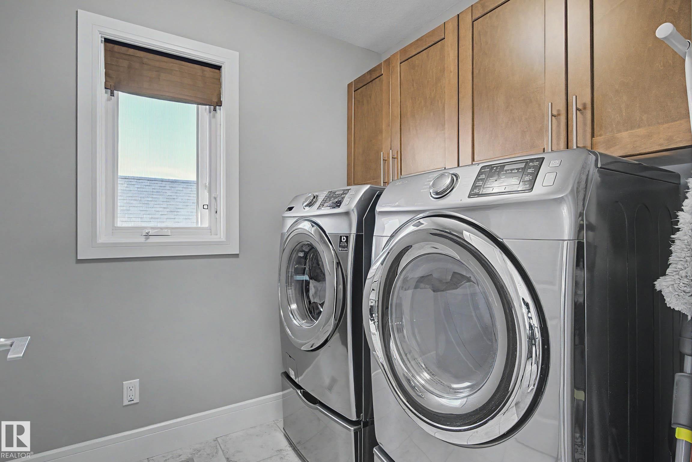 Laundry area featuring wood cabinetry, a white framed window, and light-toned flooring - 2086 Redtail Common, Edmonton, AB - Indoor Photo Showing Laundry Room