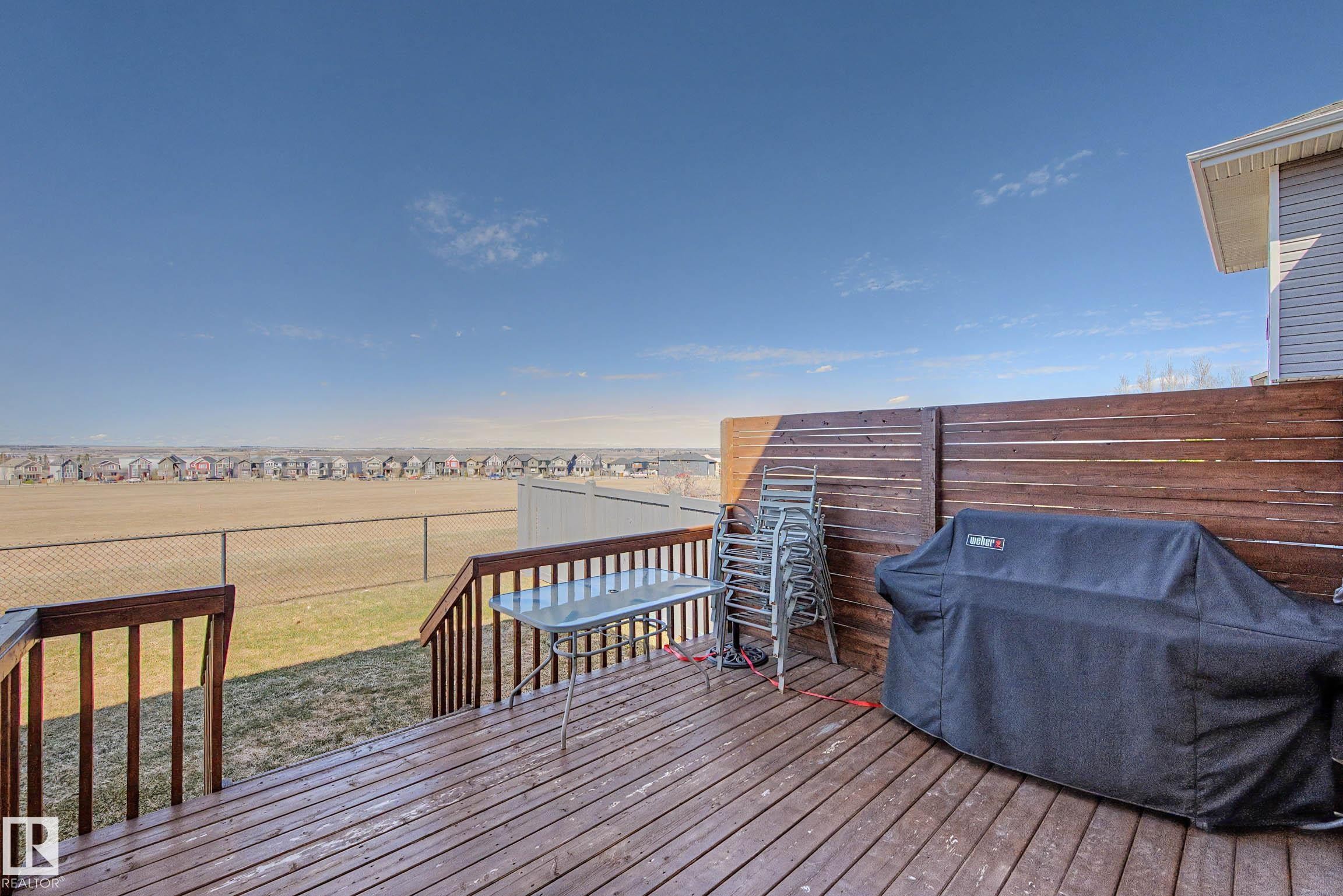 Expansive wood-finish deck featuring a privacy fence and railing overlooking open terrain - 2086 Redtail Common, Edmonton, AB - Outdoor With Deck Patio Veranda With Exterior