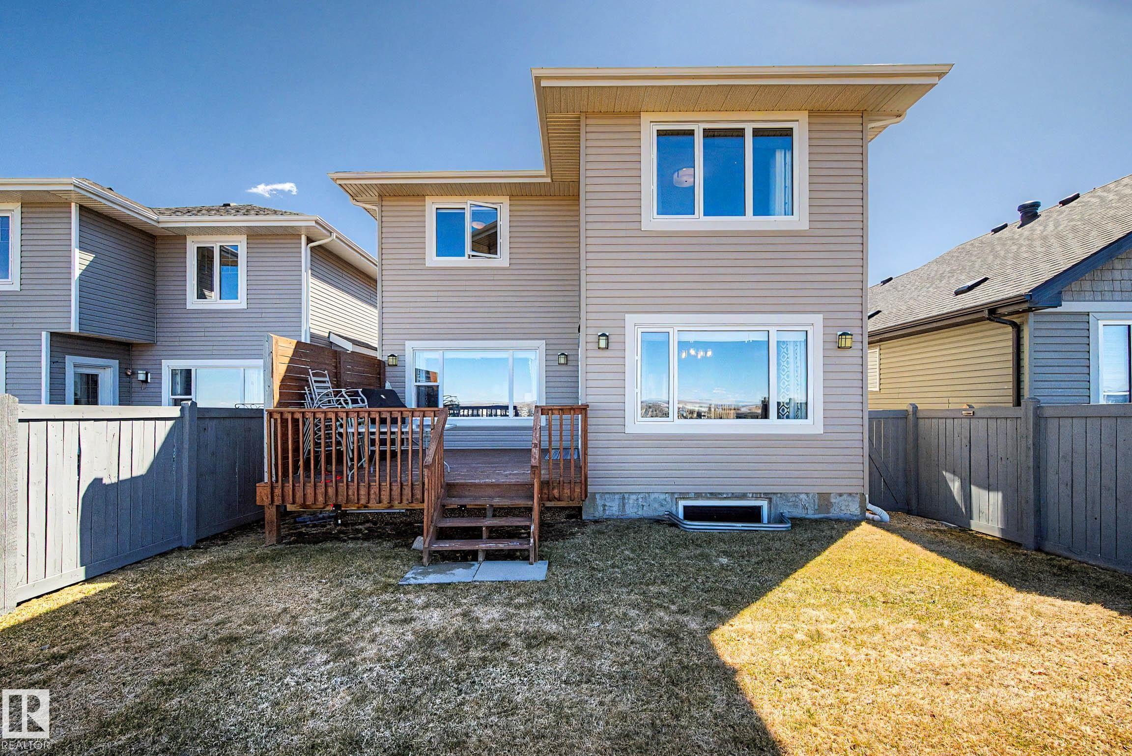 Rear exterior featuring a spacious wood deck with steps, privacy fencing, and a ground-level yard - 2086 Redtail Common, Edmonton, AB - Outdoor