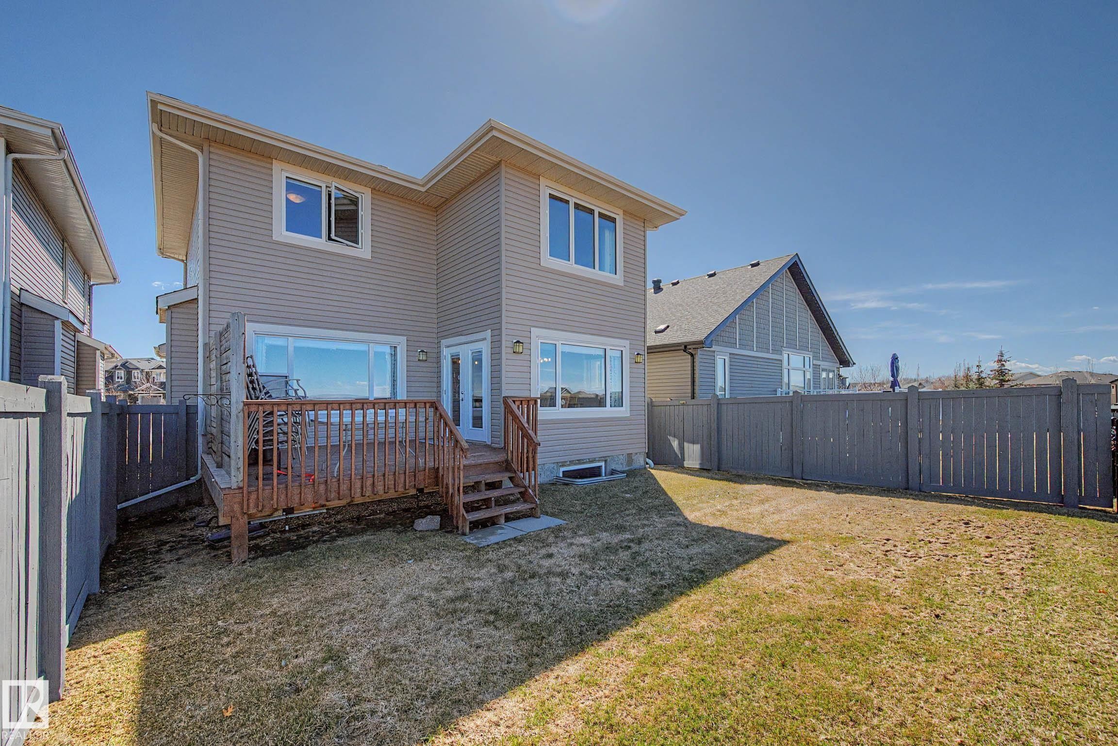 Rear exterior featuring a wooden deck with railing, dual-pane windows, and a sliding glass door - 2086 Redtail Common, Edmonton, AB - Outdoor