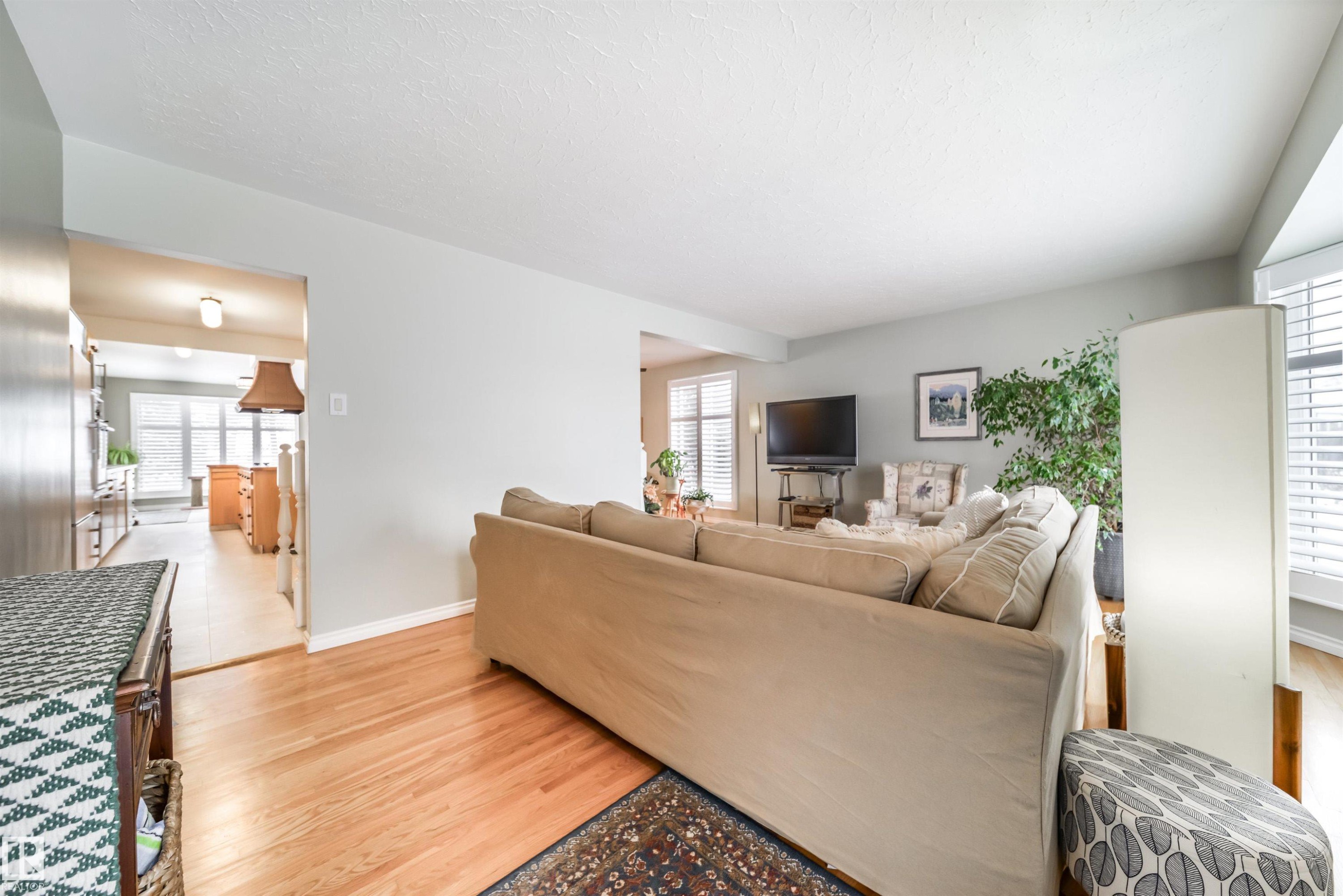 Hardwood flooring extends throughout this living space, featuring neutral wall tones and white window blinds - 10231 46 Street, Edmonton, AB - Indoor Photo Showing Living Room