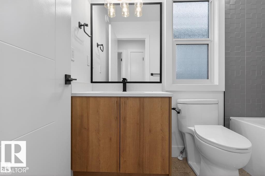 Bathroom vanity featuring a wood-finish cabinet, white countertop, and a rectangular mirror with black trim - 55 Rosa Crescent, St. Albert, AB - Indoor Photo Showing Bathroom