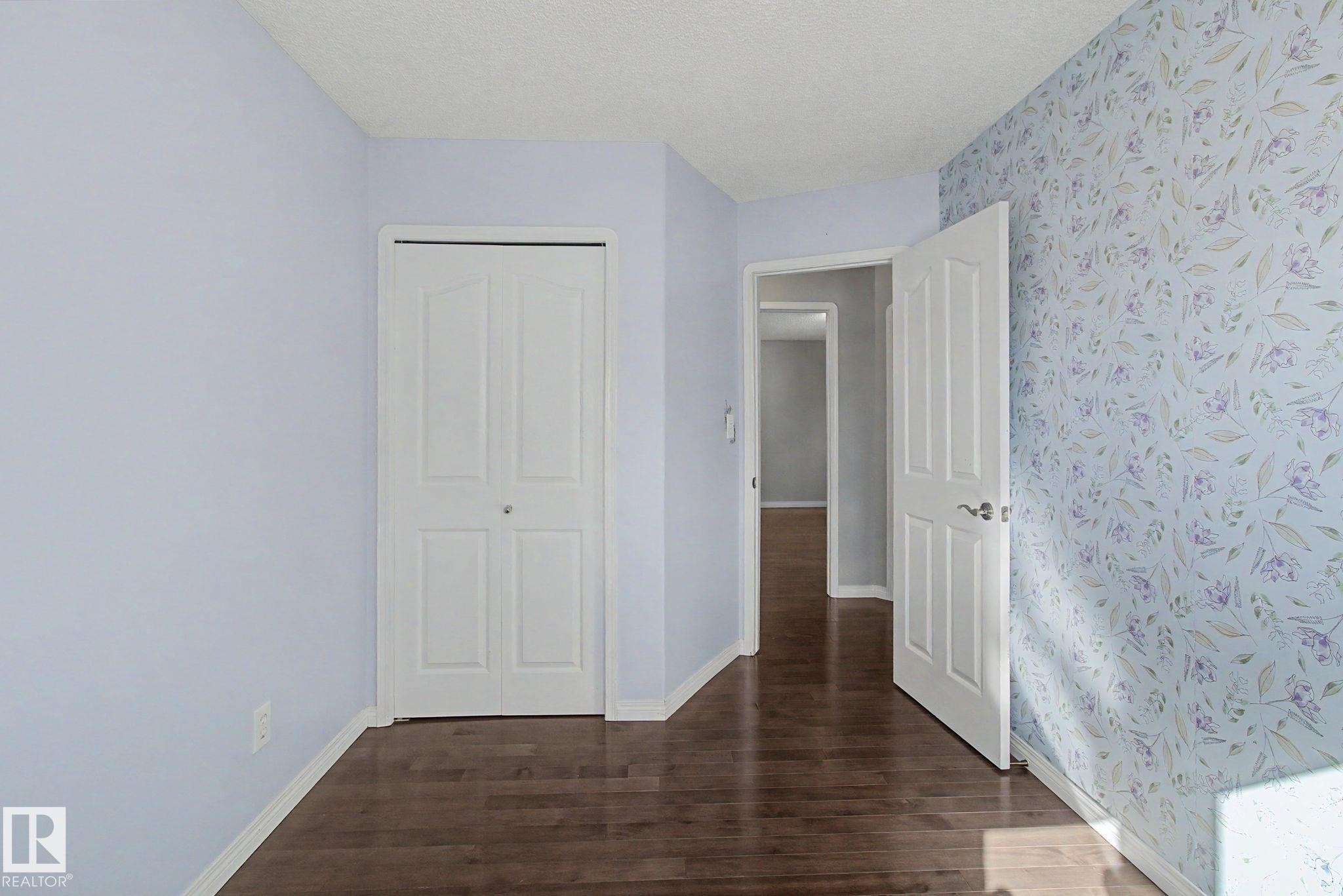 Wood-finish flooring throughout, complemented by light blue painted walls and patterned wallpaper - 3903 32 Street, Edmonton, AB - Indoor