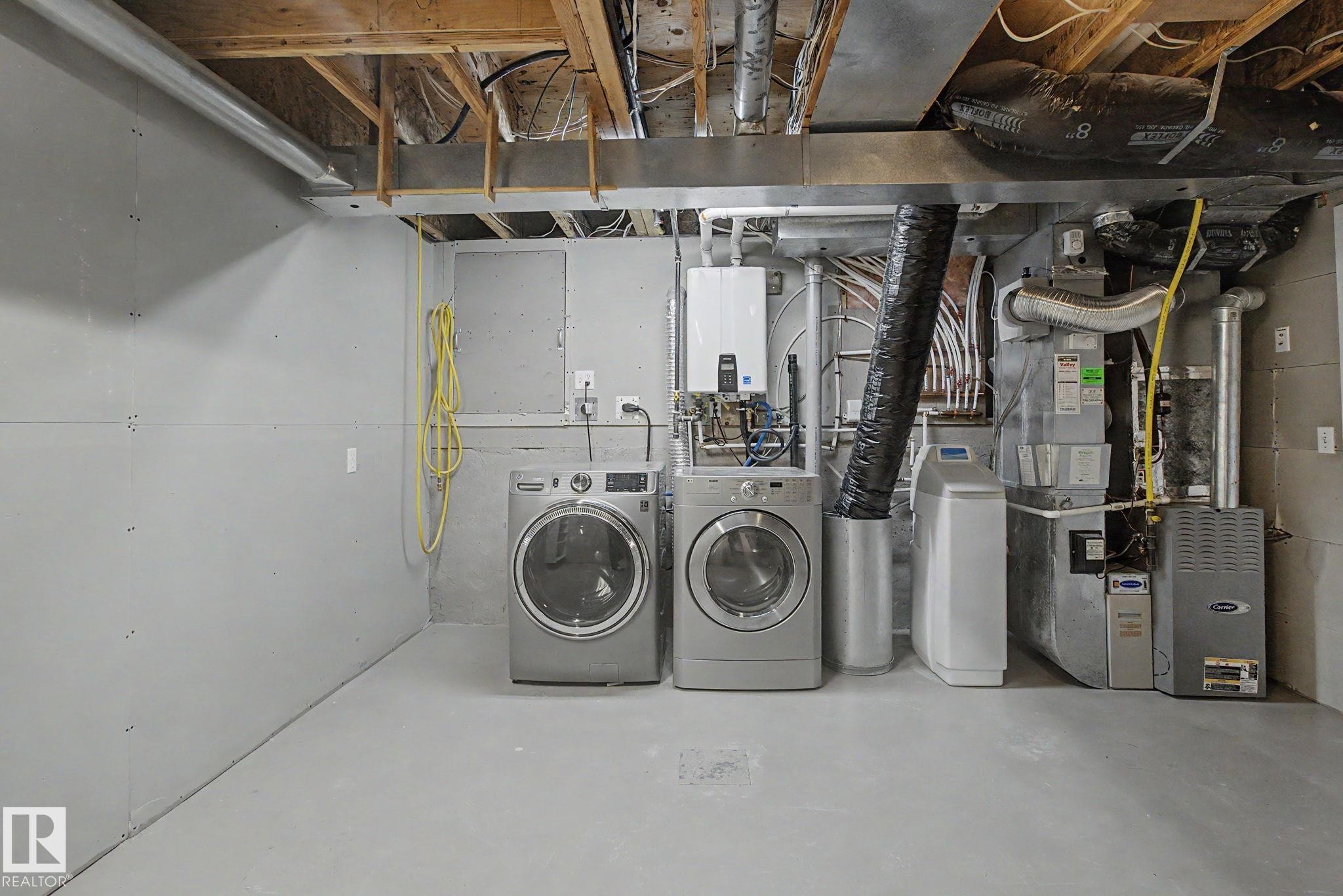 Dedicated utility area featuring washer and dryer appliances, tankless water heater, water softener system, and furnace - 3903 32 Street, Edmonton, AB - Indoor Photo Showing Laundry Room
