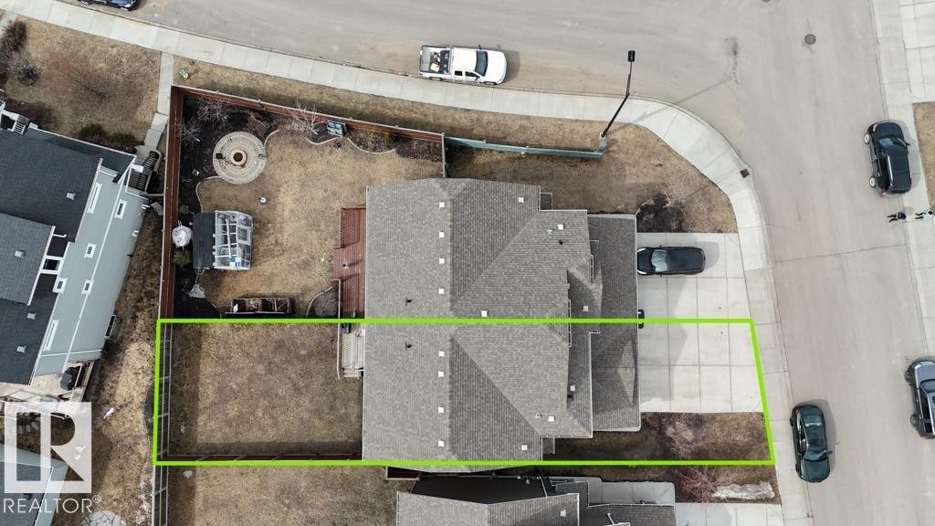 Aerial view highlighting the property boundaries, a multi-gabled roofline, concrete driveway, and a rear yard with a fire pit area - 16619 14 Avenue, Edmonton, AB -
