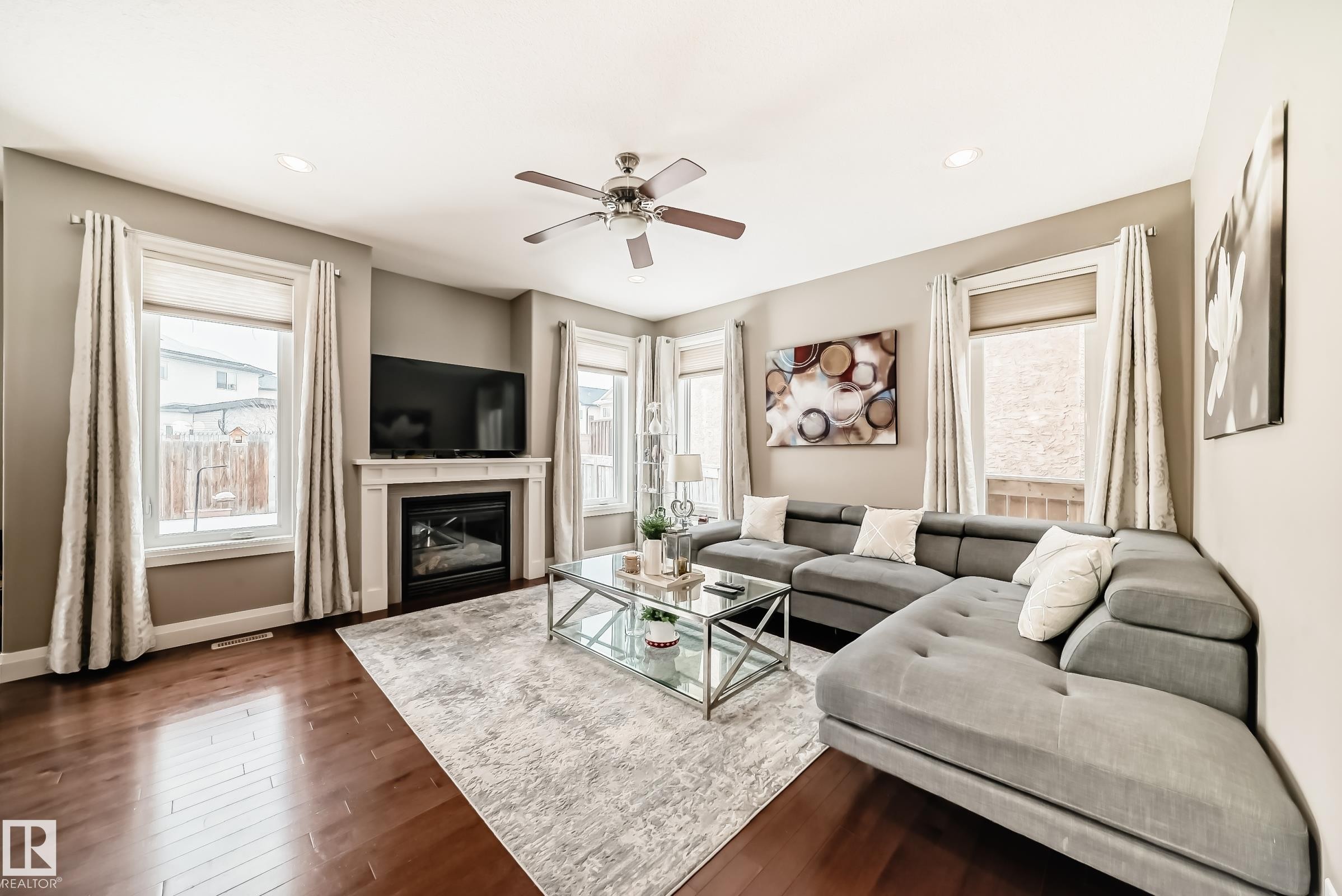 This living area features hardwood floors and a fireplace with a white mantel - 3220 151 Avenue, Edmonton, AB - Indoor Photo Showing Living Room With Fireplace