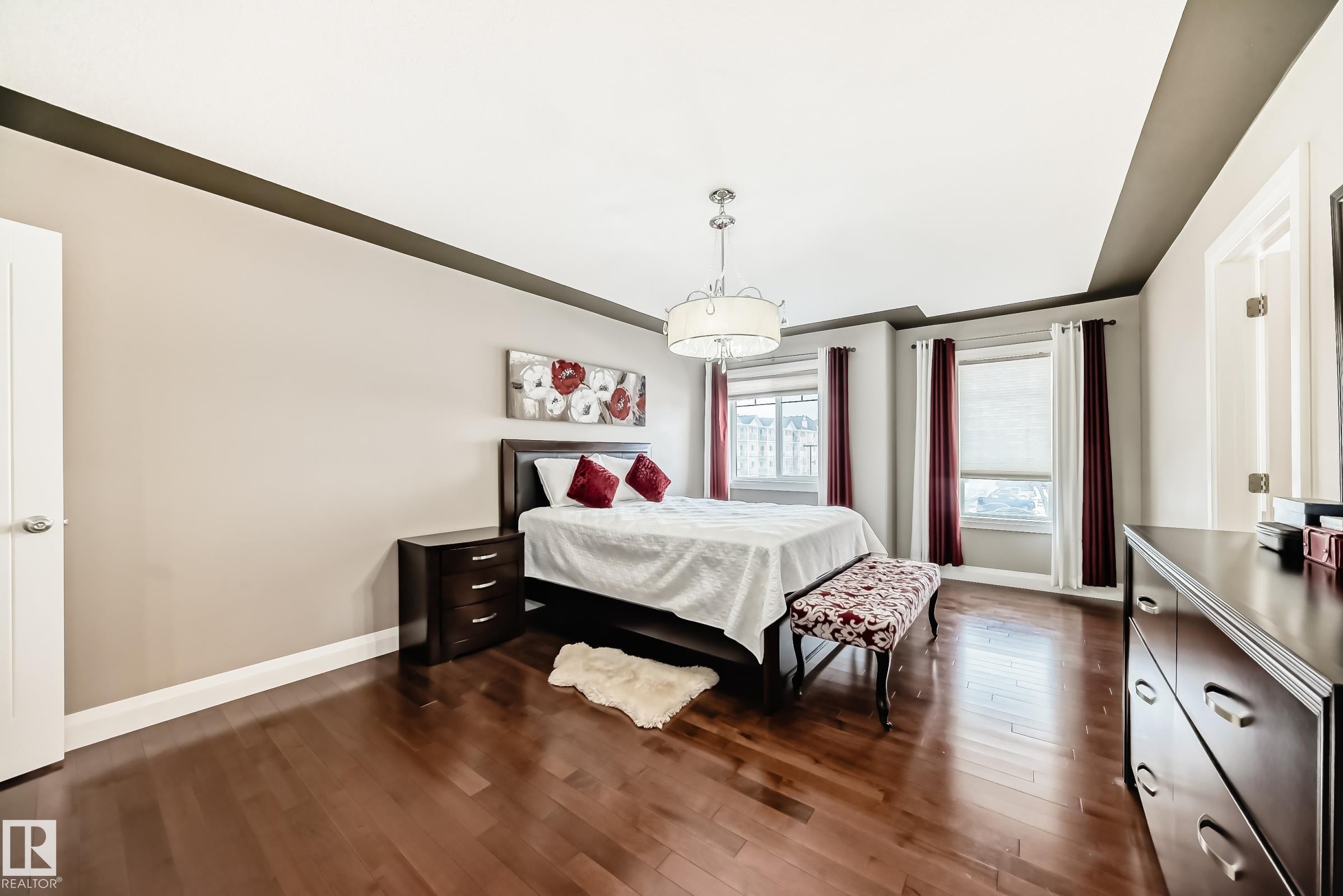 This bedroom features rich hardwood flooring, light neutral walls, and a tray ceiling - 3220 151 Avenue, Edmonton, AB - Indoor Photo Showing Bedroom