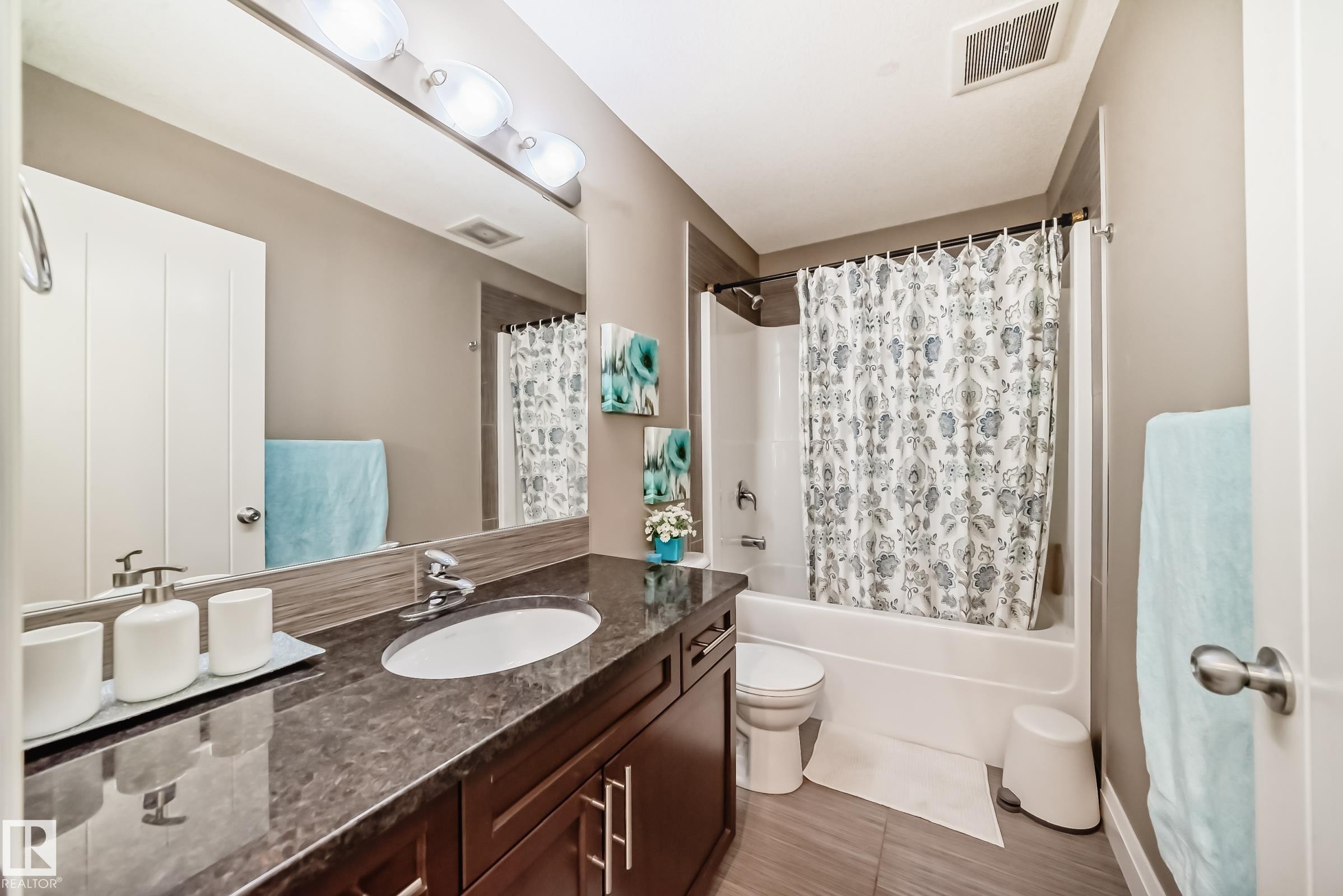 Bathroom featuring a vanity with a dark countertop and cabinetry, a large mirror, and a shower/tub combination - 3220 151 Avenue, Edmonton, AB - Indoor Photo Showing Bathroom