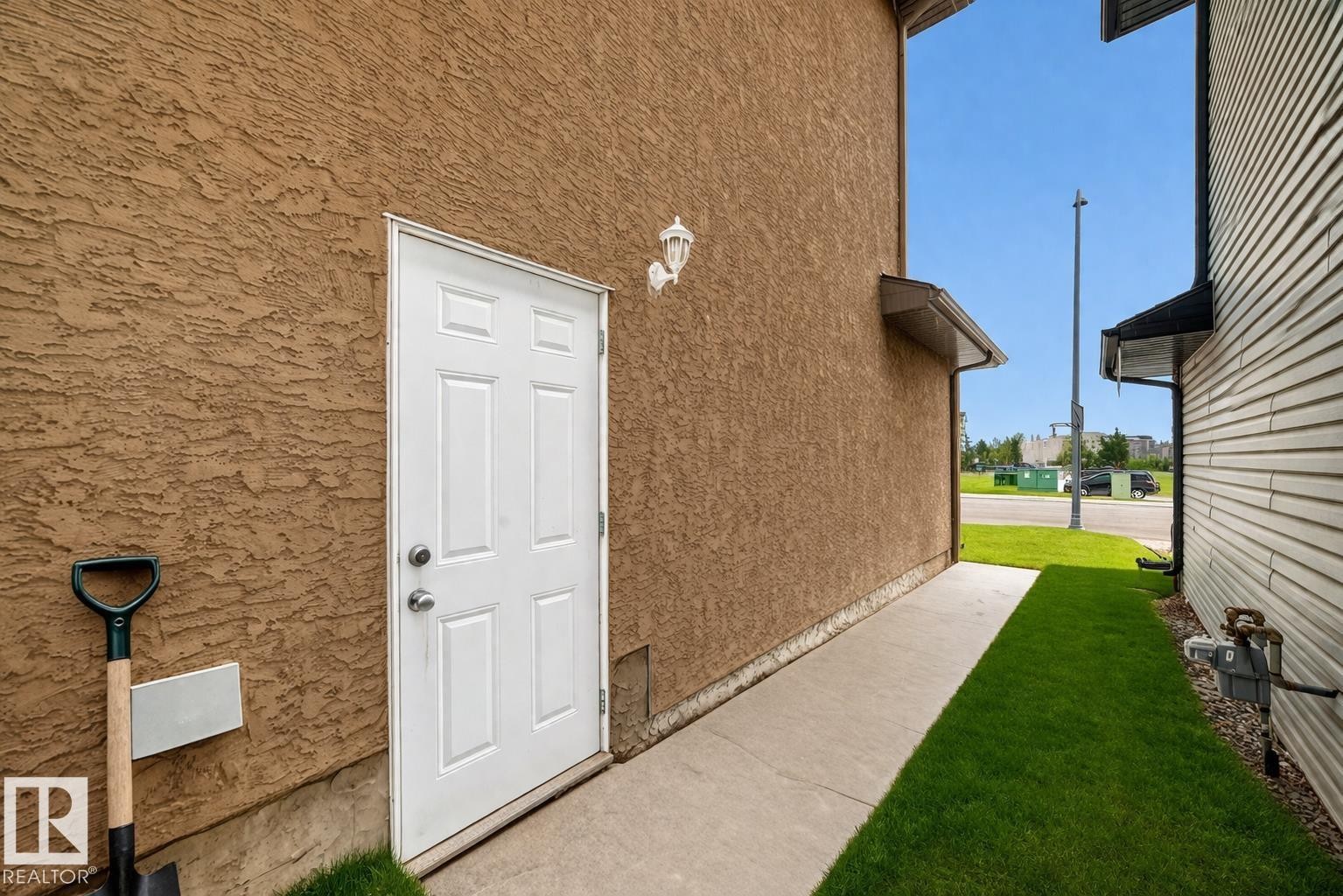 The property features a white paneled door set within a stucco exterior wall - 3220 151 Avenue, Edmonton, AB - Outdoor With Exterior