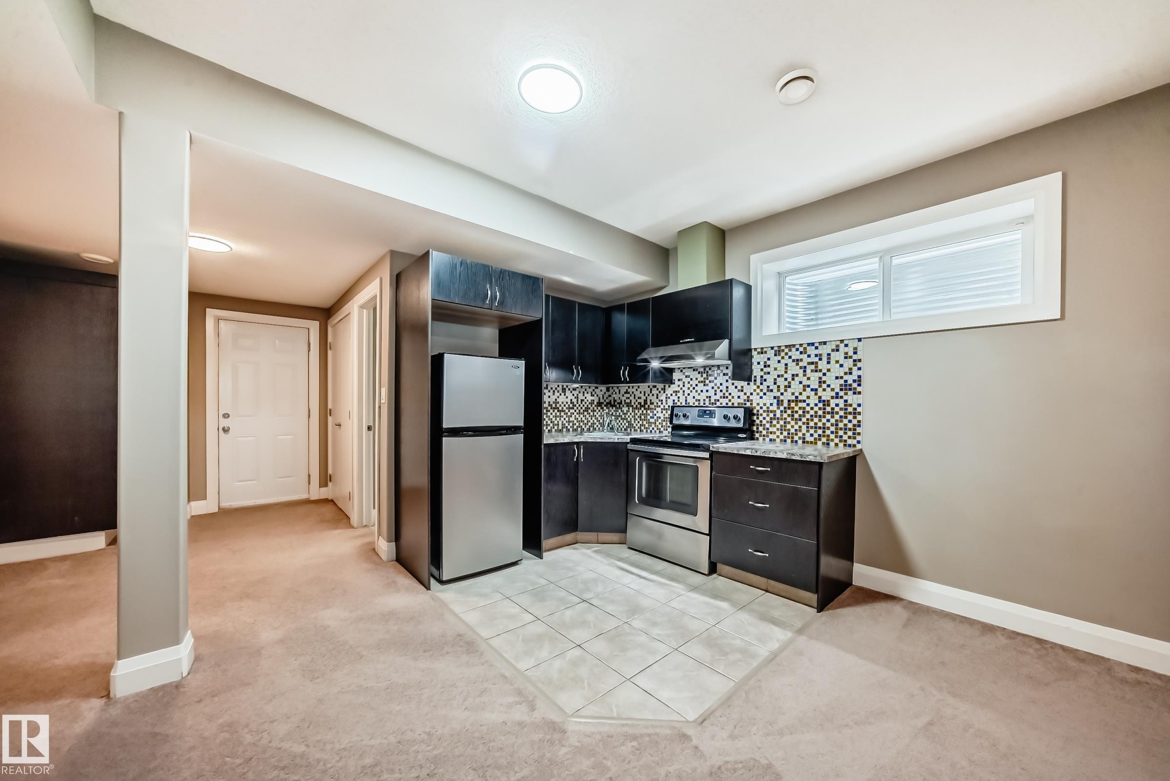 Kitchenette featuring dark cabinetry, stainless steel appliances, and a tiled backsplash - 3220 151 Avenue, Edmonton, AB - Indoor Photo Showing Kitchen
