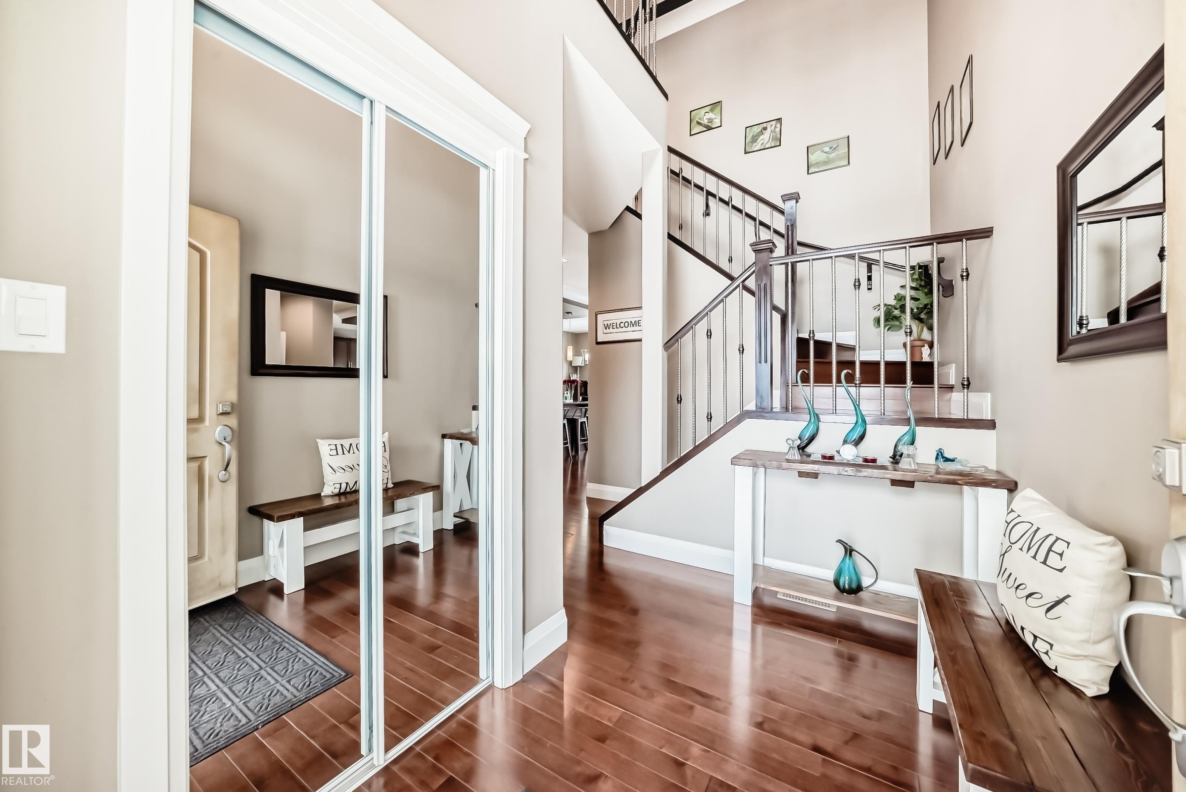 Entryway featuring hardwood flooring, a staircase with wooden handrails and metal balusters, and a mirrored closet with sliding doors - 3220 151 Avenue, Edmonton, AB - Indoor Photo Showing Other Room