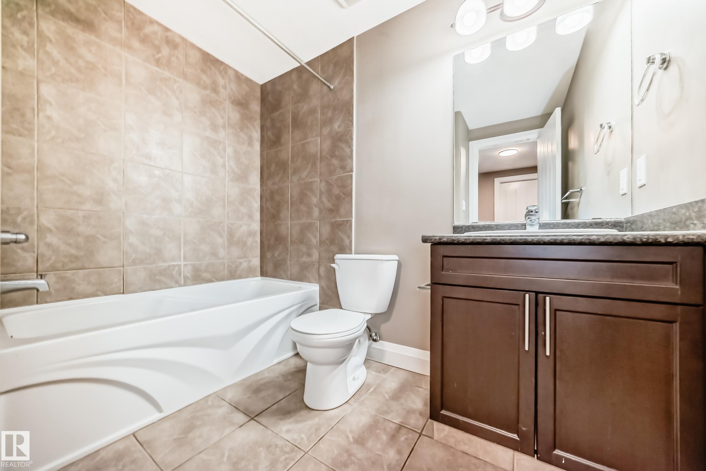 Bathroom featuring a white bathtub, tiled walls, and tiled flooring - 3220 151 Avenue, Edmonton, AB - Indoor Photo Showing Bathroom