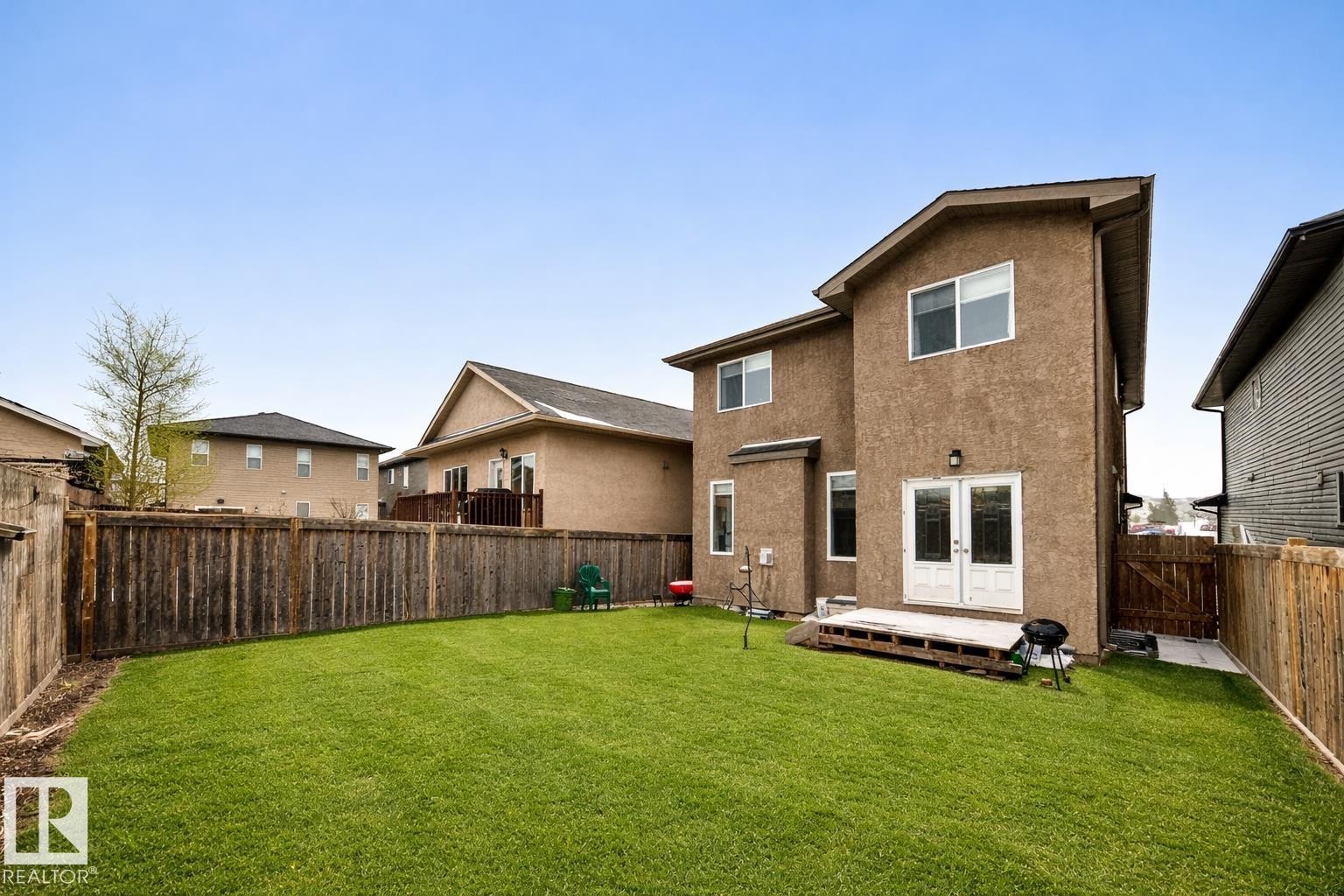 The property features a spacious backyard with a well-maintained lawn and a wooden fence - 3220 151 Avenue, Edmonton, AB - Outdoor With Exterior