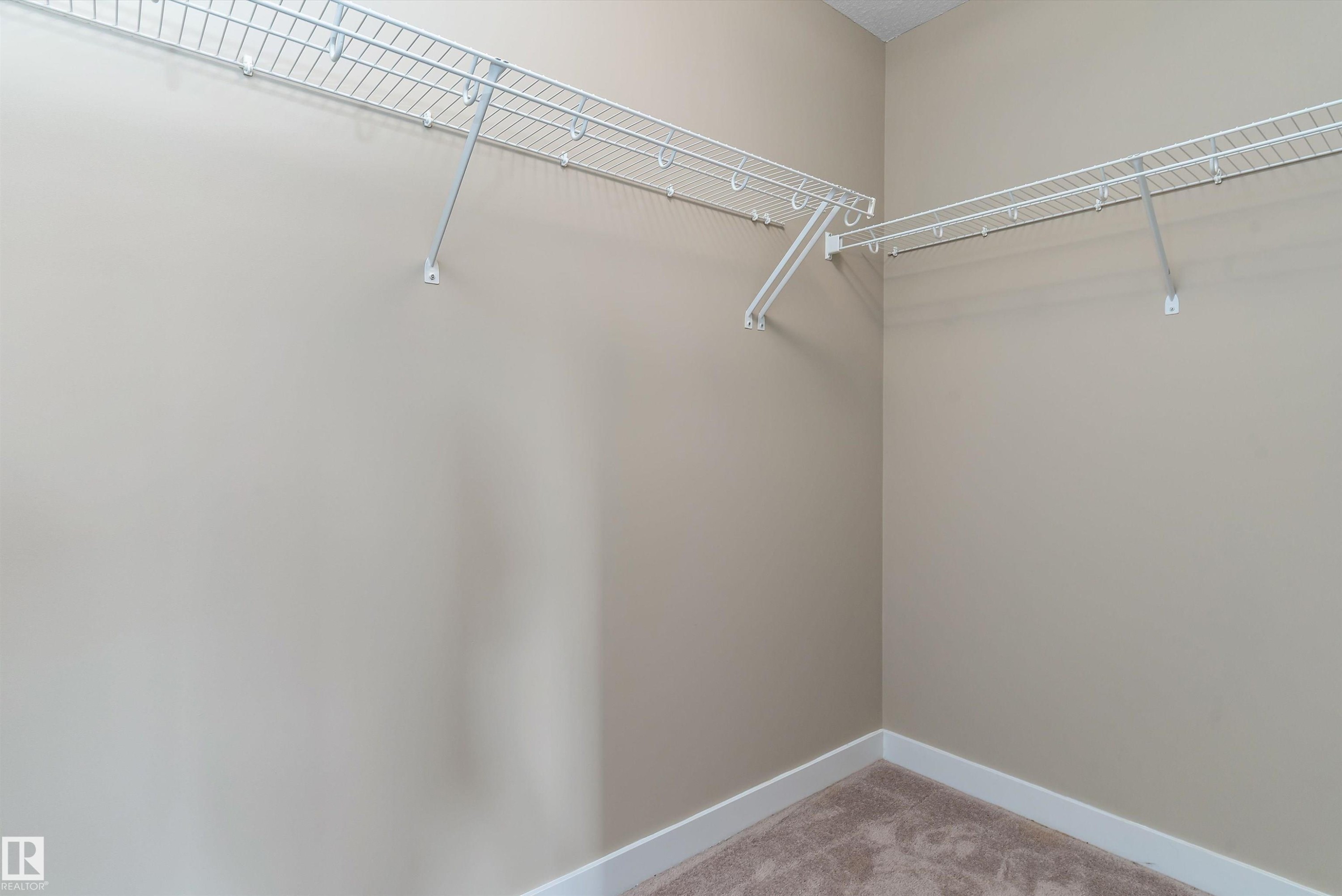 Walk-in closet featuring wire shelving, beige wall paint, white baseboards, and carpet flooring - 3314 9 Street Nw, Edmonton, AB - Indoor With Storage