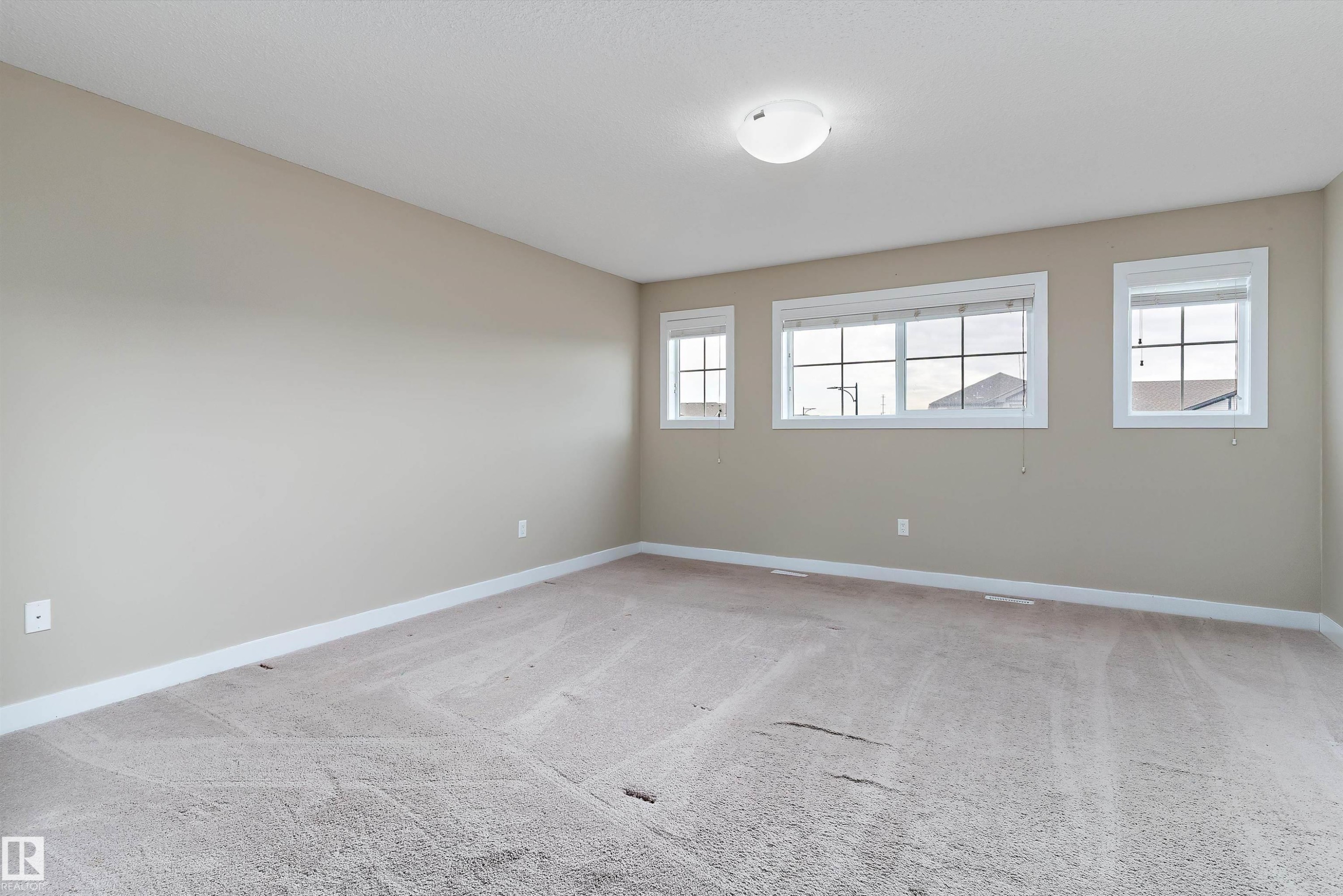 Neutral tone wall paint, light-colored carpet flooring, white trim, multiple windows, and a flush mount ceiling light - 3314 9 Street Nw, Edmonton, AB - Indoor Photo Showing Other Room