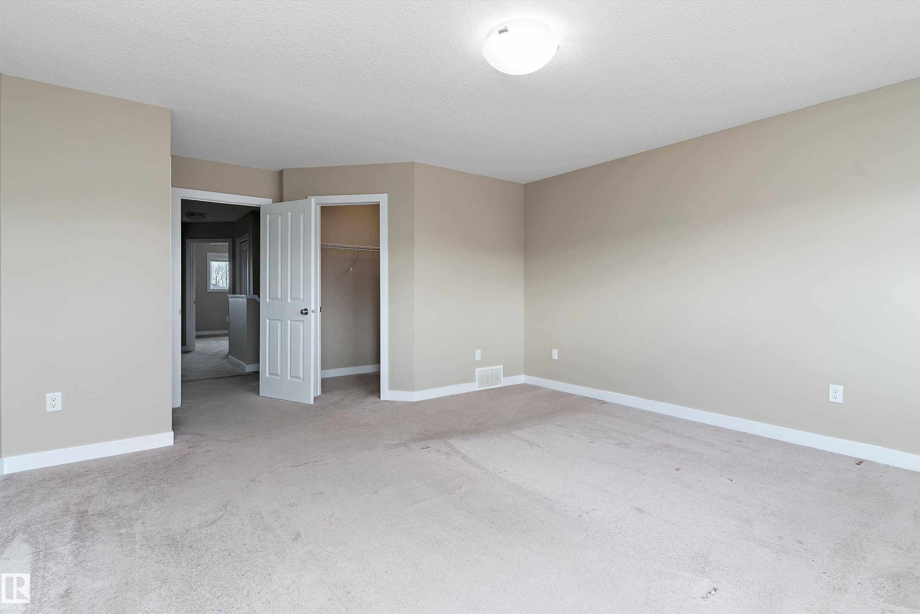 Carpeted room featuring neutral wall paint, white baseboards, and a flush-mount ceiling light fixture - 3314 9 Street Nw, Edmonton, AB - Indoor Photo Showing Other Room