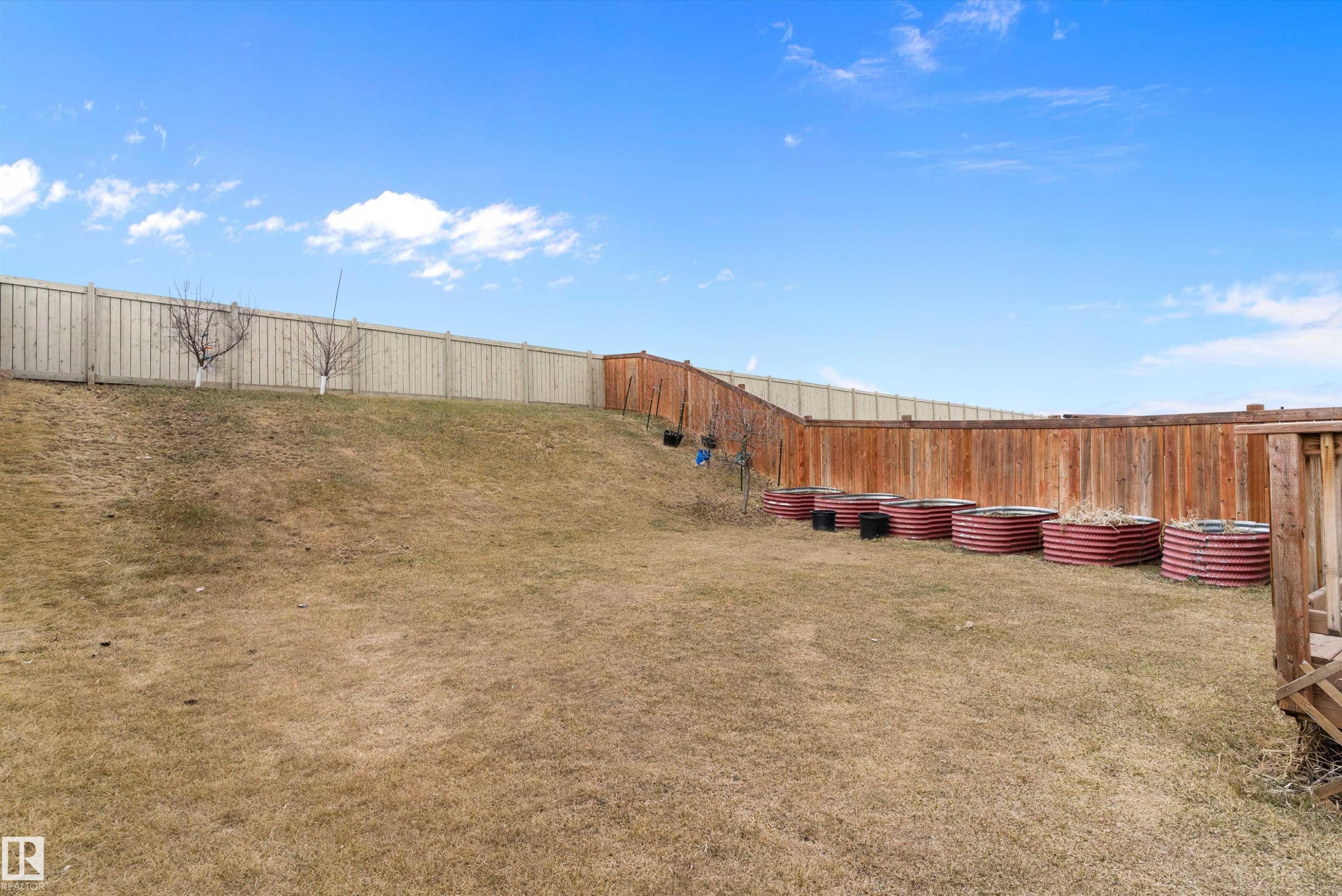 Expansive backyard featuring a partial wood fence, a partial stained wood fence, and a series of circular garden beds - 3314 9 Street Nw, Edmonton, AB - Outdoor