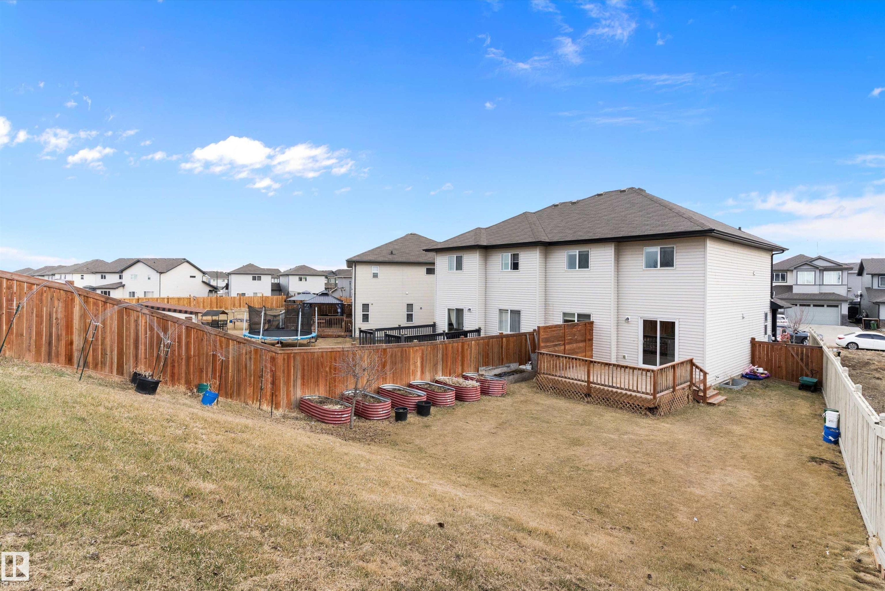 Expansive backyard featuring a wood deck, full privacy fencing, and raised garden beds - 3314 9 Street Nw, Edmonton, AB - Outdoor