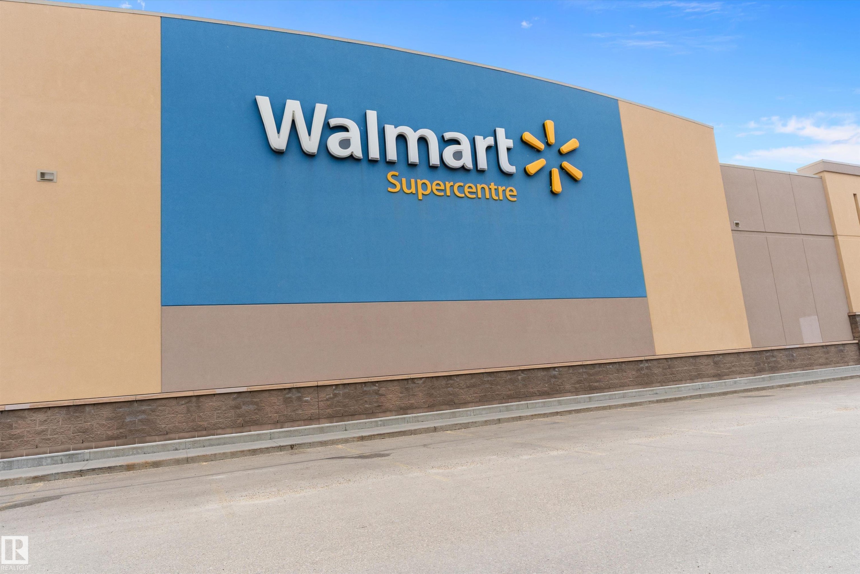 Commercial property featuring a large blue facade with prominent signage, complemented by neutral-toned stucco and a dark stone-finish base - 3314 9 Street Nw, Edmonton, AB -