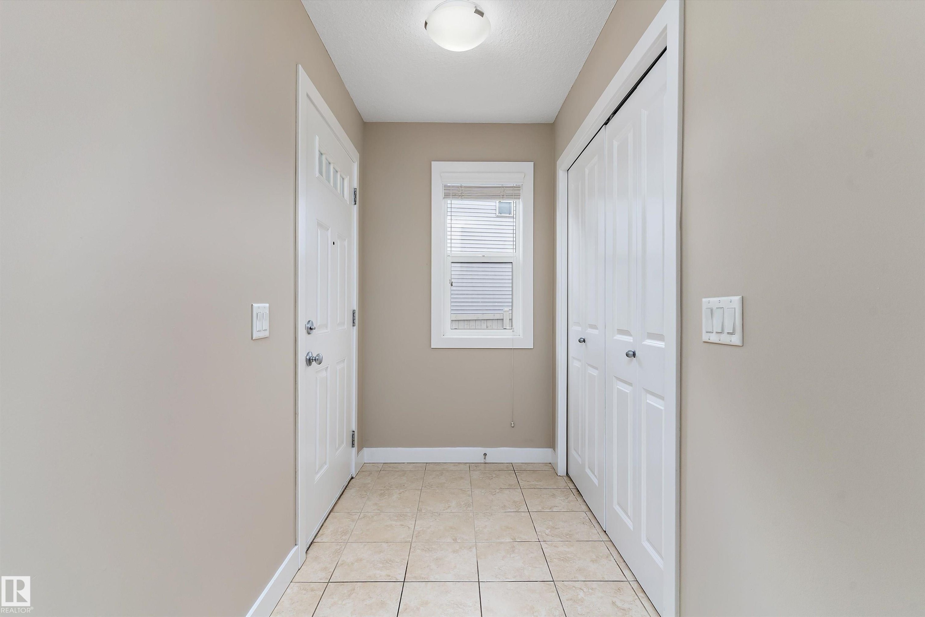 Entryway featuring neutral wall paint, tiled flooring, a window with blinds, a front door with decorative glass inserts, and a bifold closet door - 3314 9 Street Nw, Edmonton, AB - Indoor Photo Showing Other Room